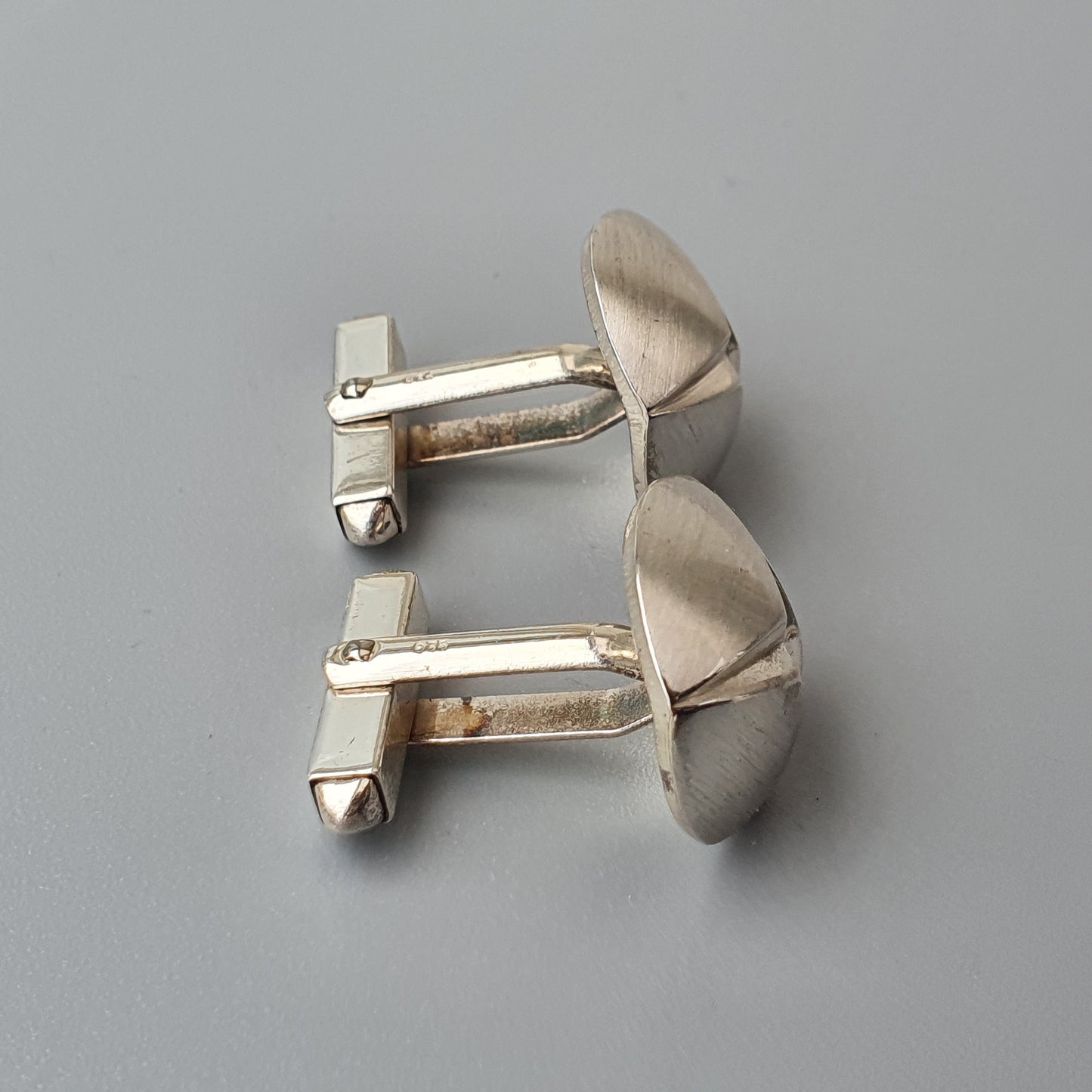 Pair of silver-colored metal cufflinks with curved oval faces.