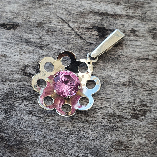 Silver flower-shaped pendant with a pink gemstone center.