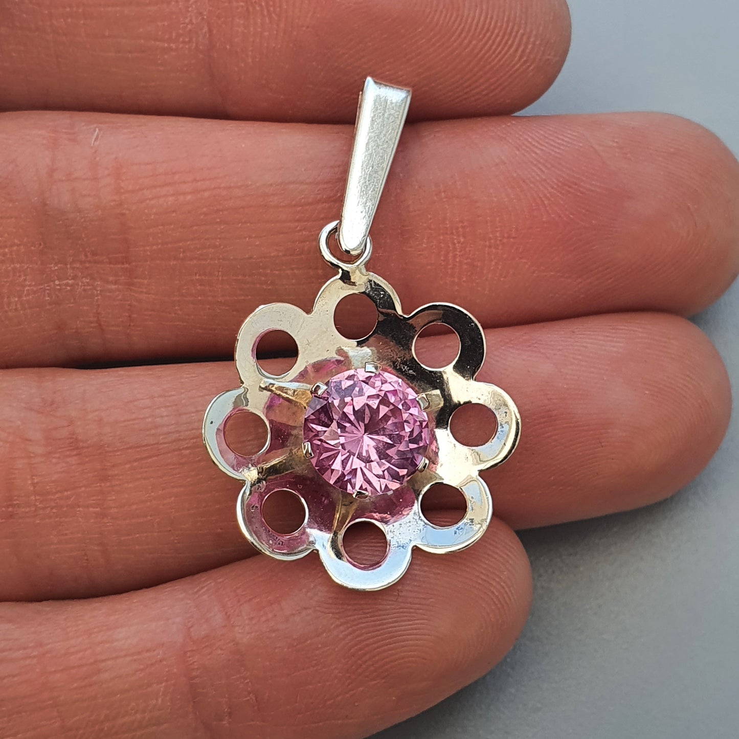 Silver flower-shaped pendant with a pink gemstone in the center.