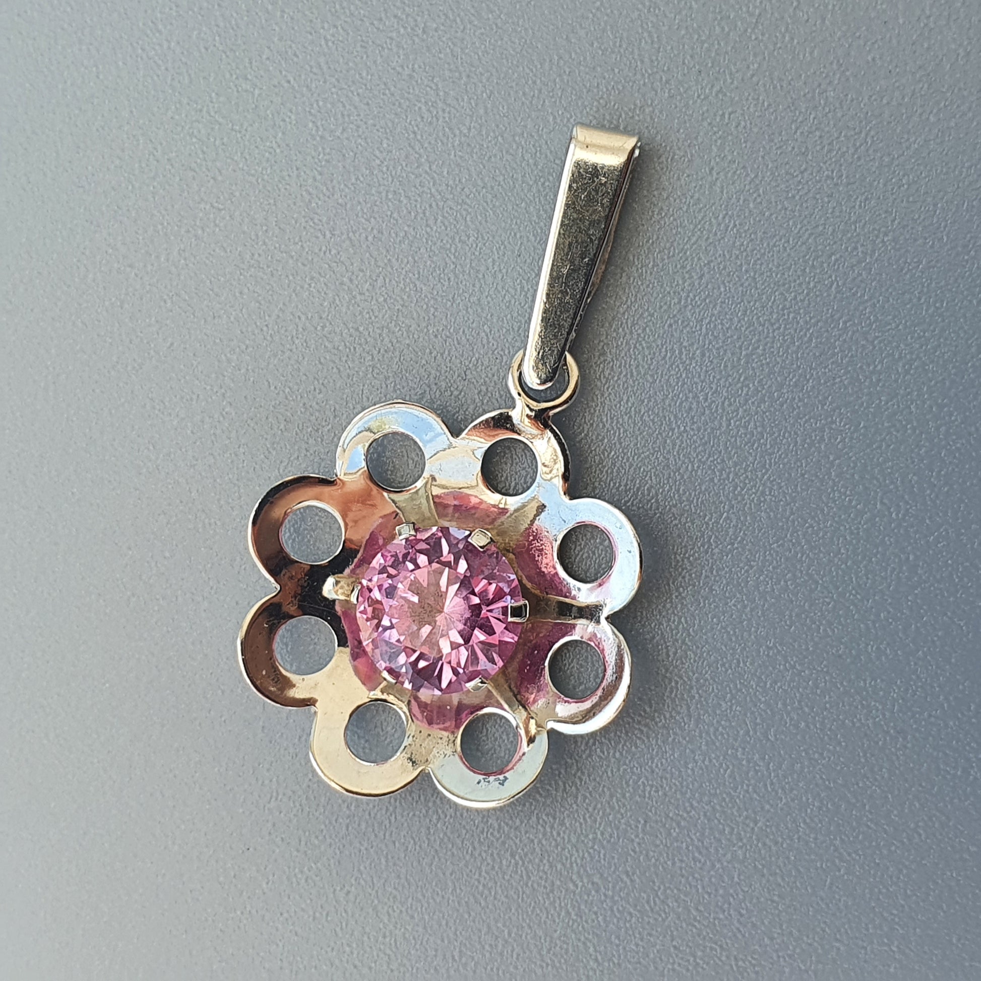 Silver flower-shaped pendant with a pink gemstone center.