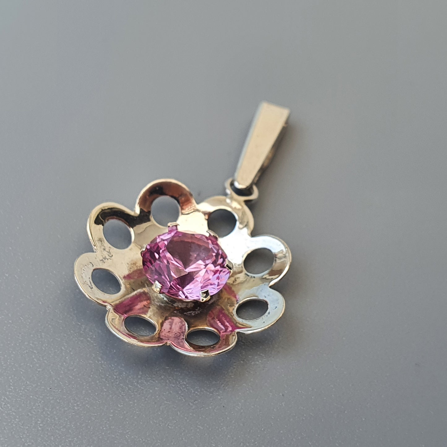 Flower-shaped silver pendant with a pink gemstone center.