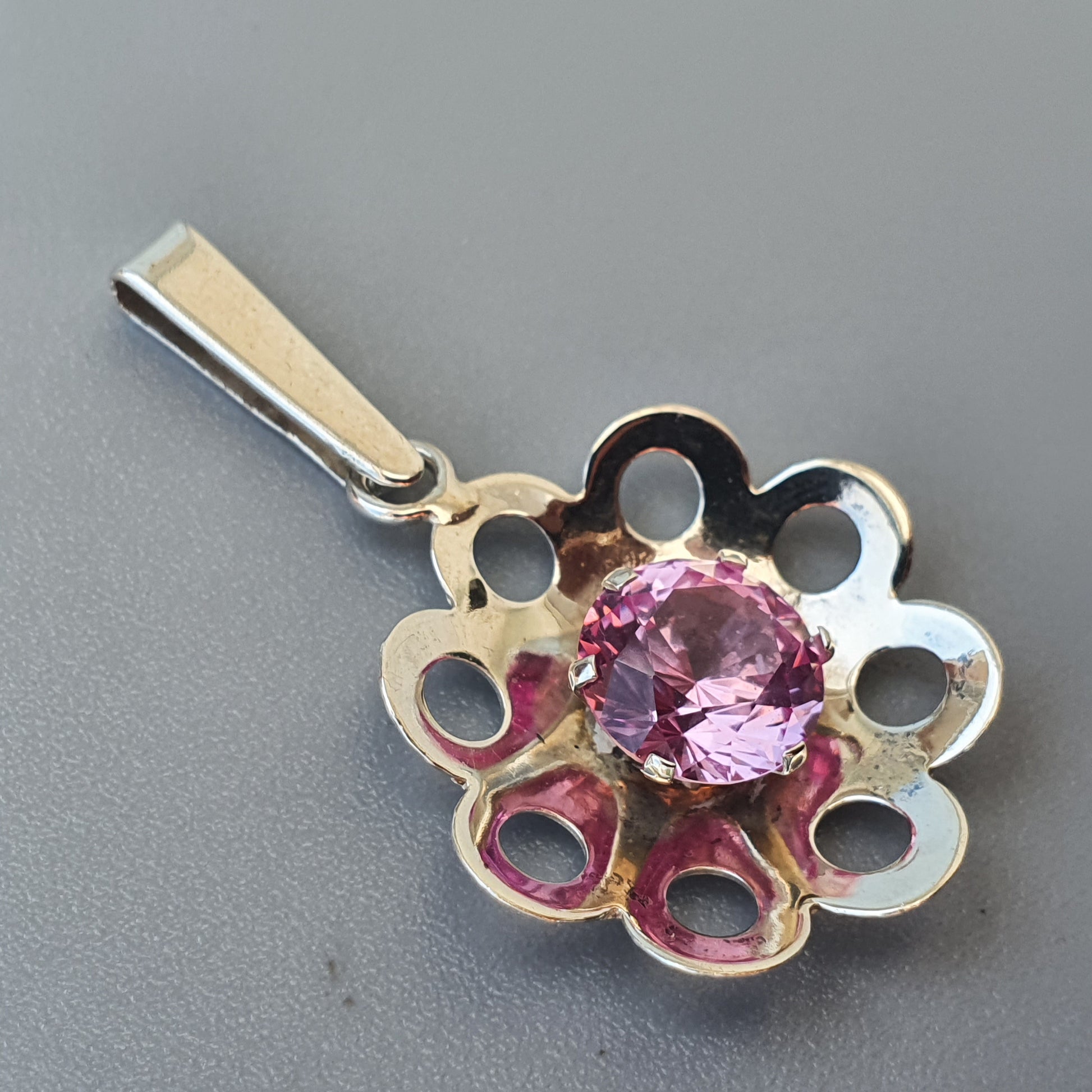 Silver flower-shaped pendant with a pink gemstone in the center.