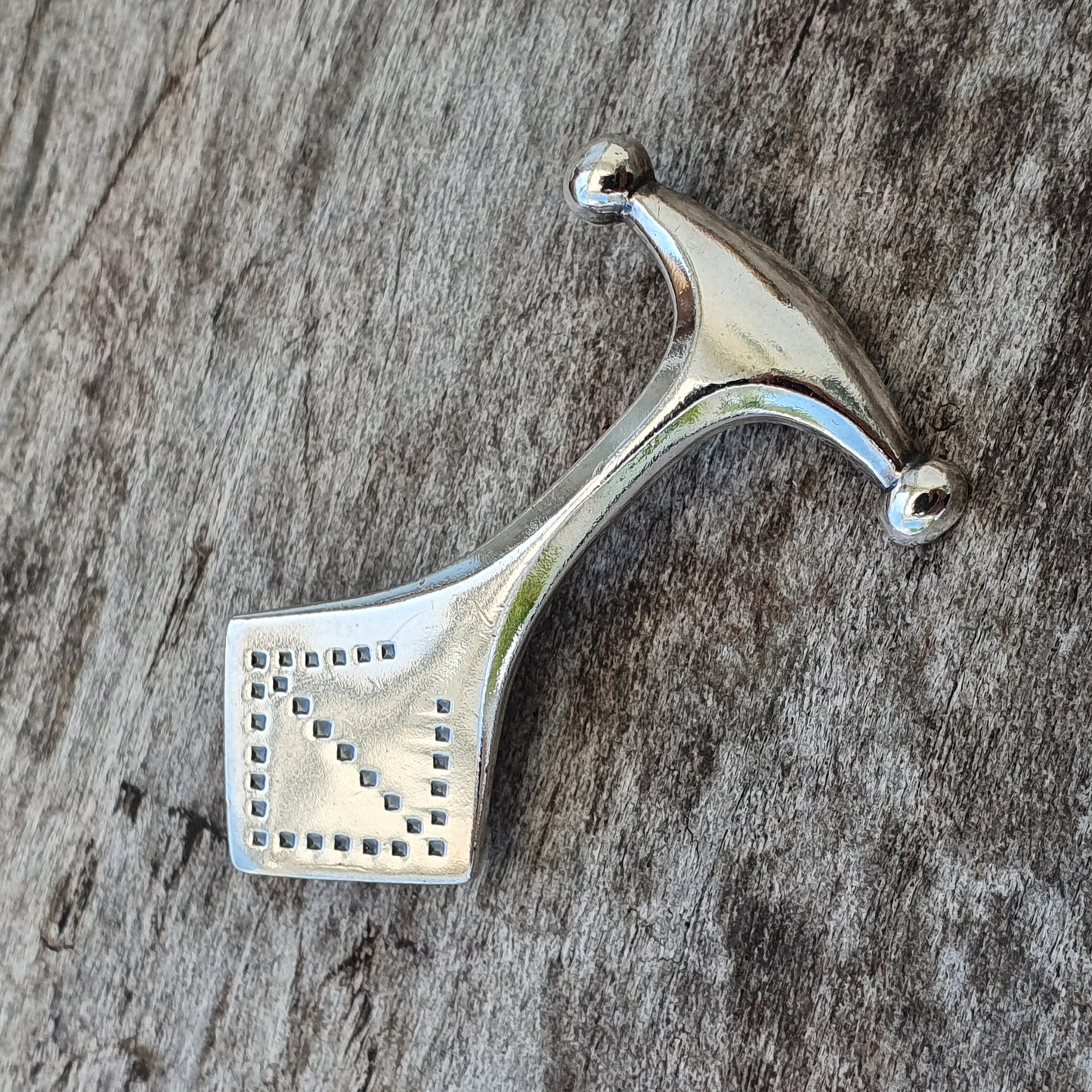 Silver pendant with a stylized hammer or axe shape featuring a perforated square design.