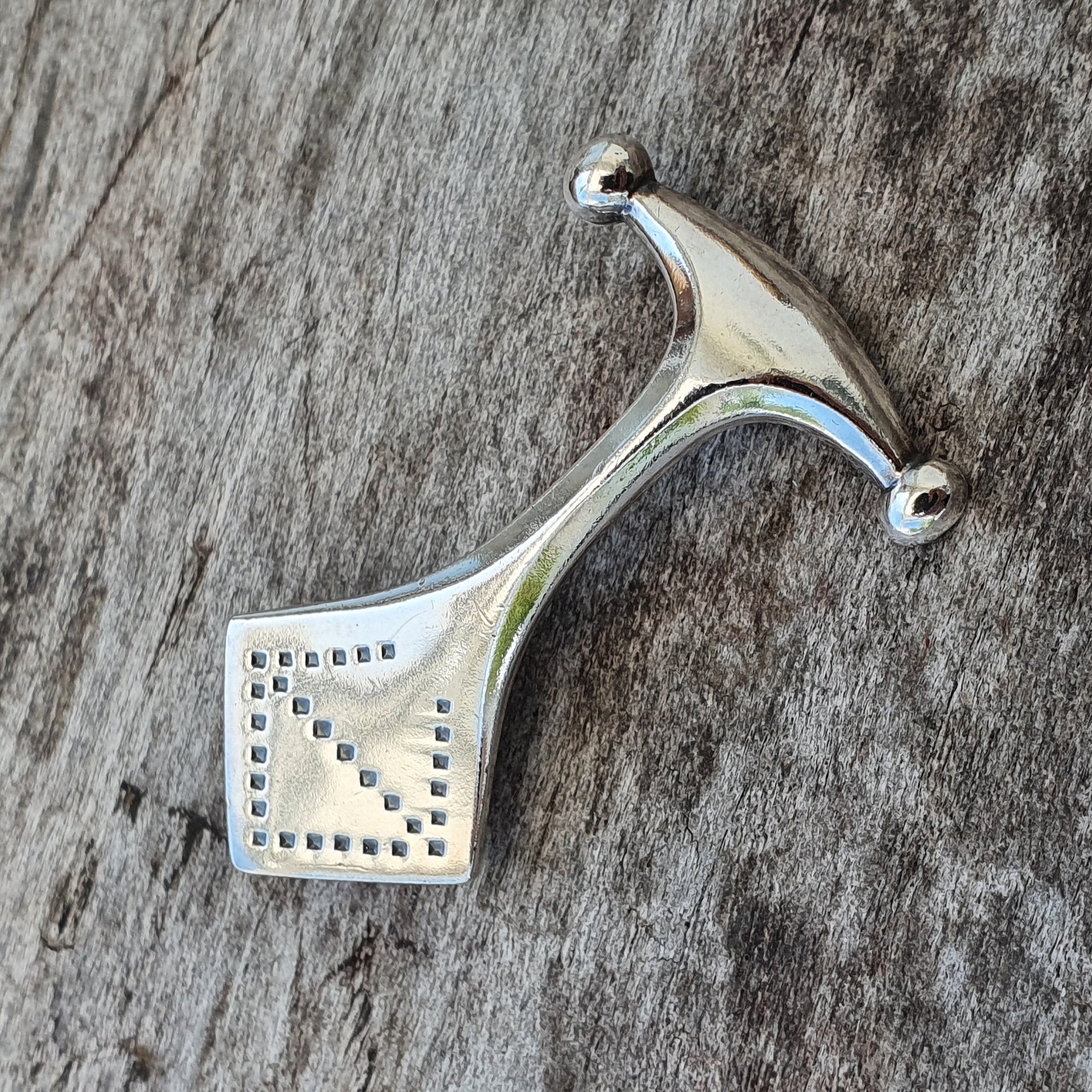 Silver pendant with a stylized hammer or axe shape featuring a perforated square design.