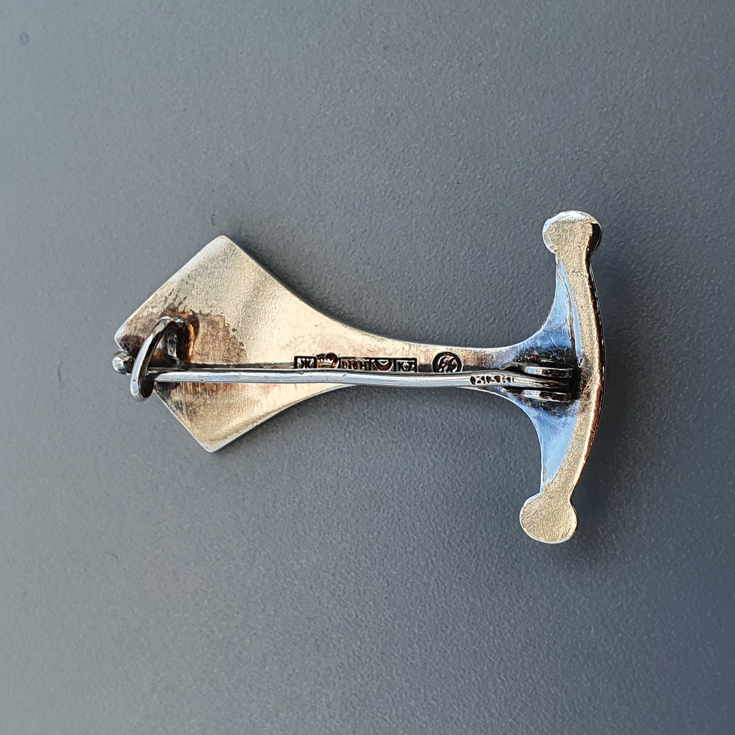 Bone-shaped metal door handle or hook mounted on a wall.