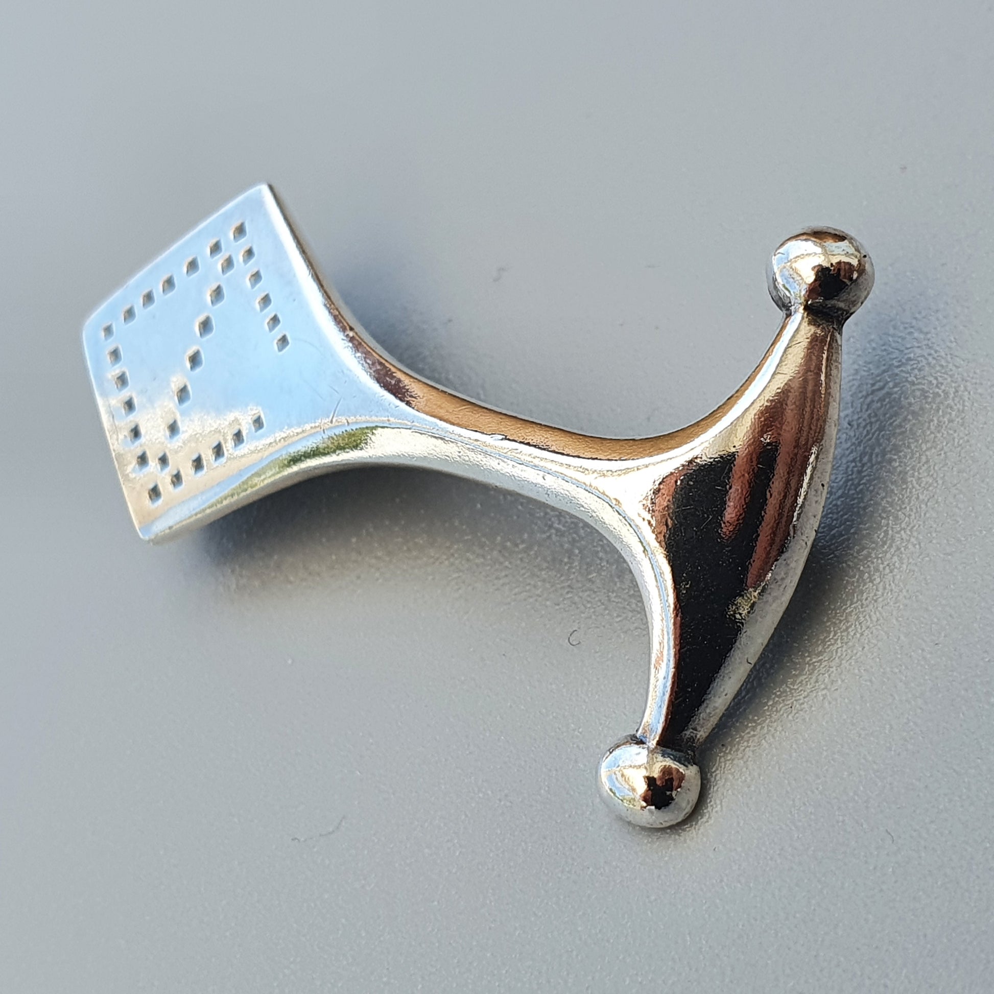 Metallic nose clip with a perforated rectangular pad attached to one end.