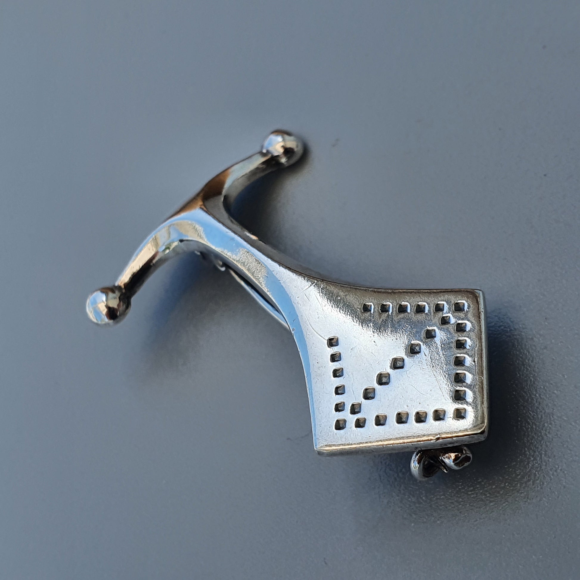 Silver pendant shaped like a stylized horse with perforated geometric designs.