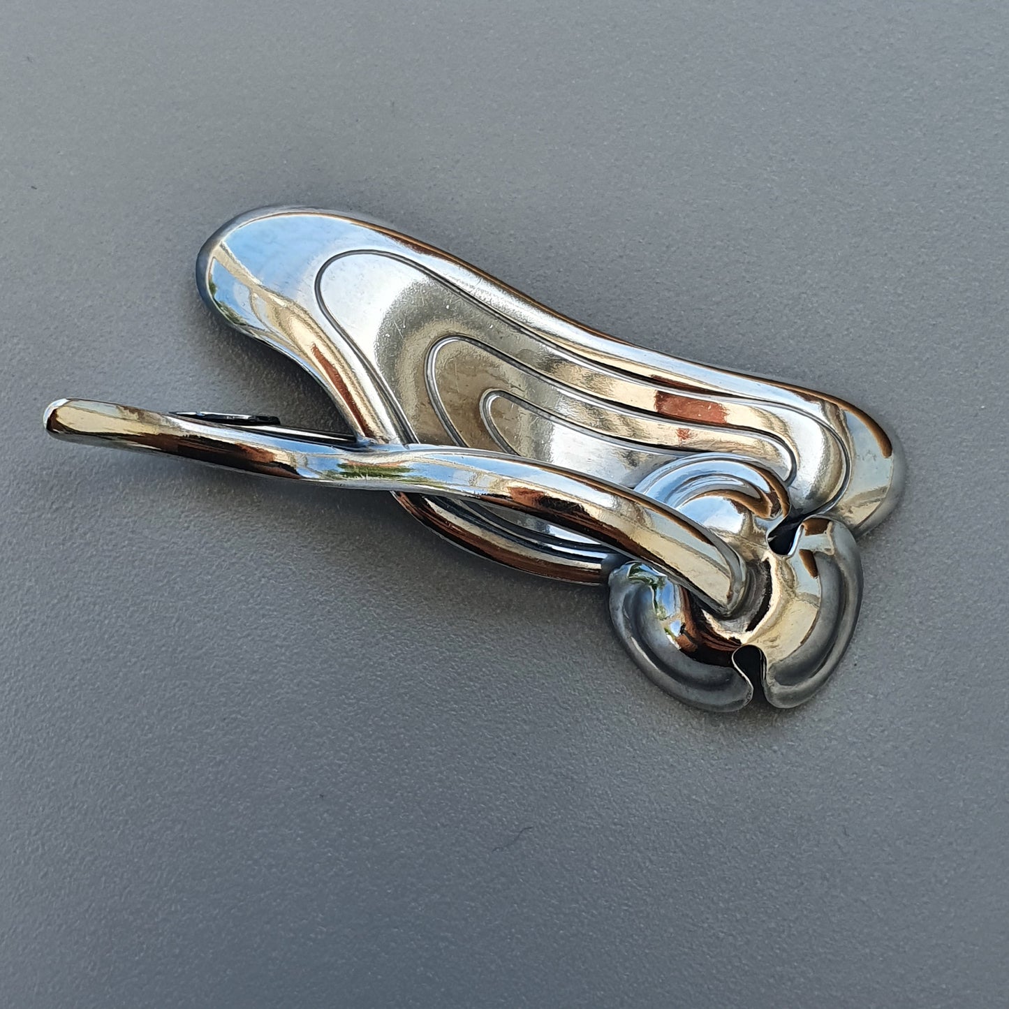 Shiny metallic keychain or key fob with a curved, organic shape.