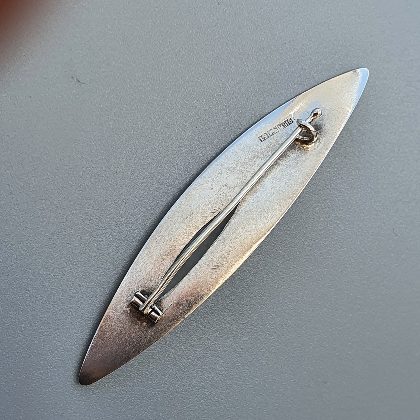 Elongated silver brooch or pin with a sleek, leaf-like shape.