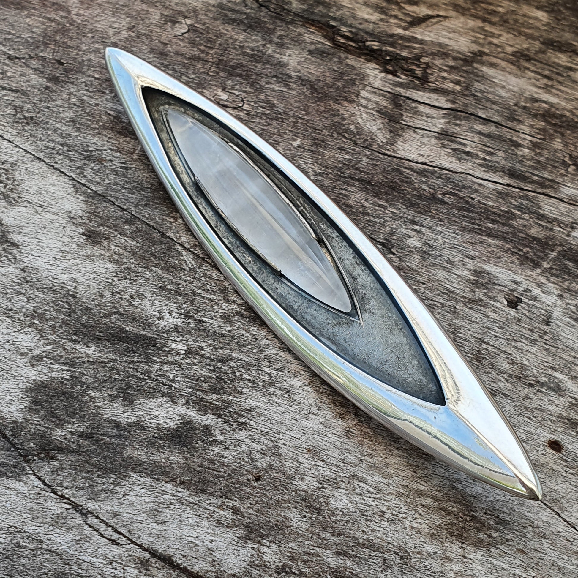 Sleek, elongated metal object with a pointed shape and central oval inlay.