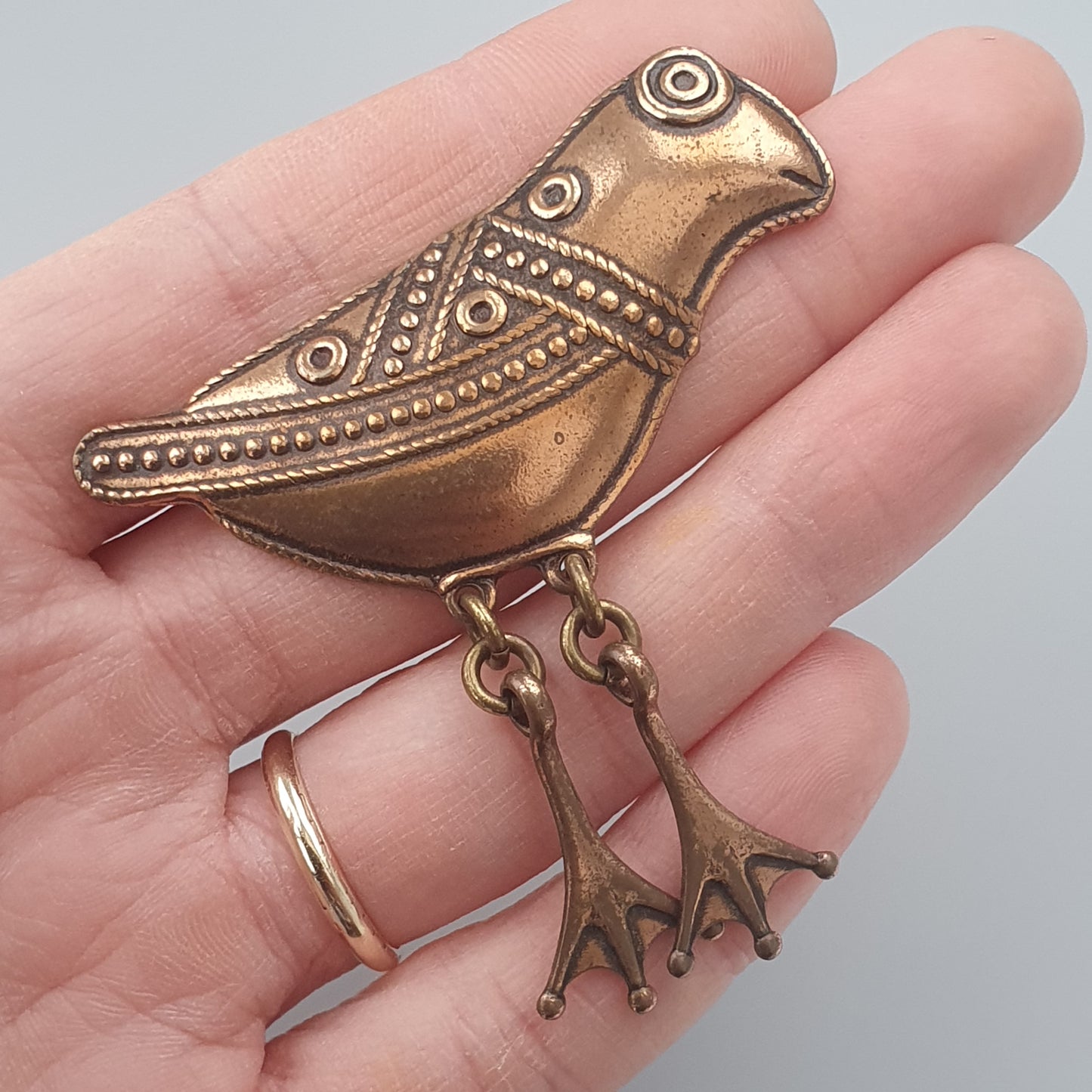 Ornate bronze bird-shaped brooch with dangling feet charms.