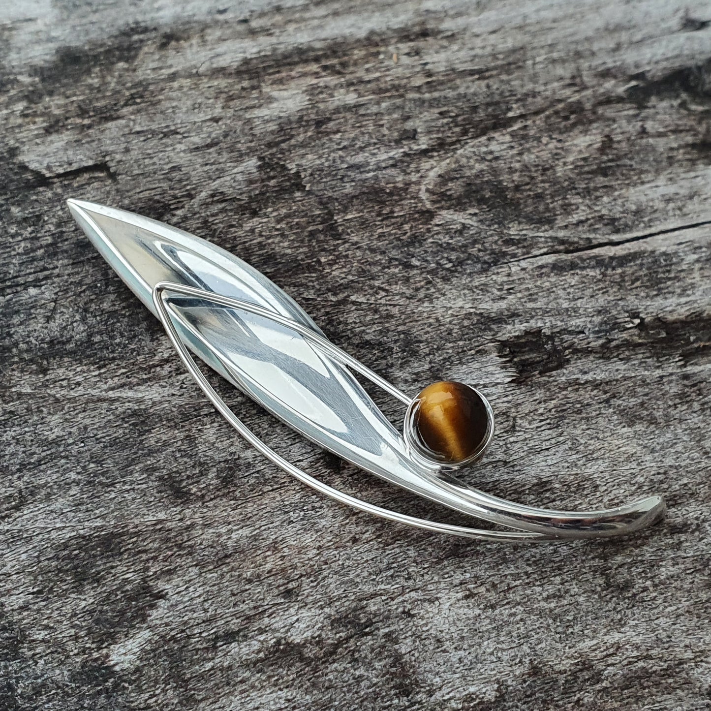 Elegant silver leaf-shaped brooch with a round amber-colored gemstone.