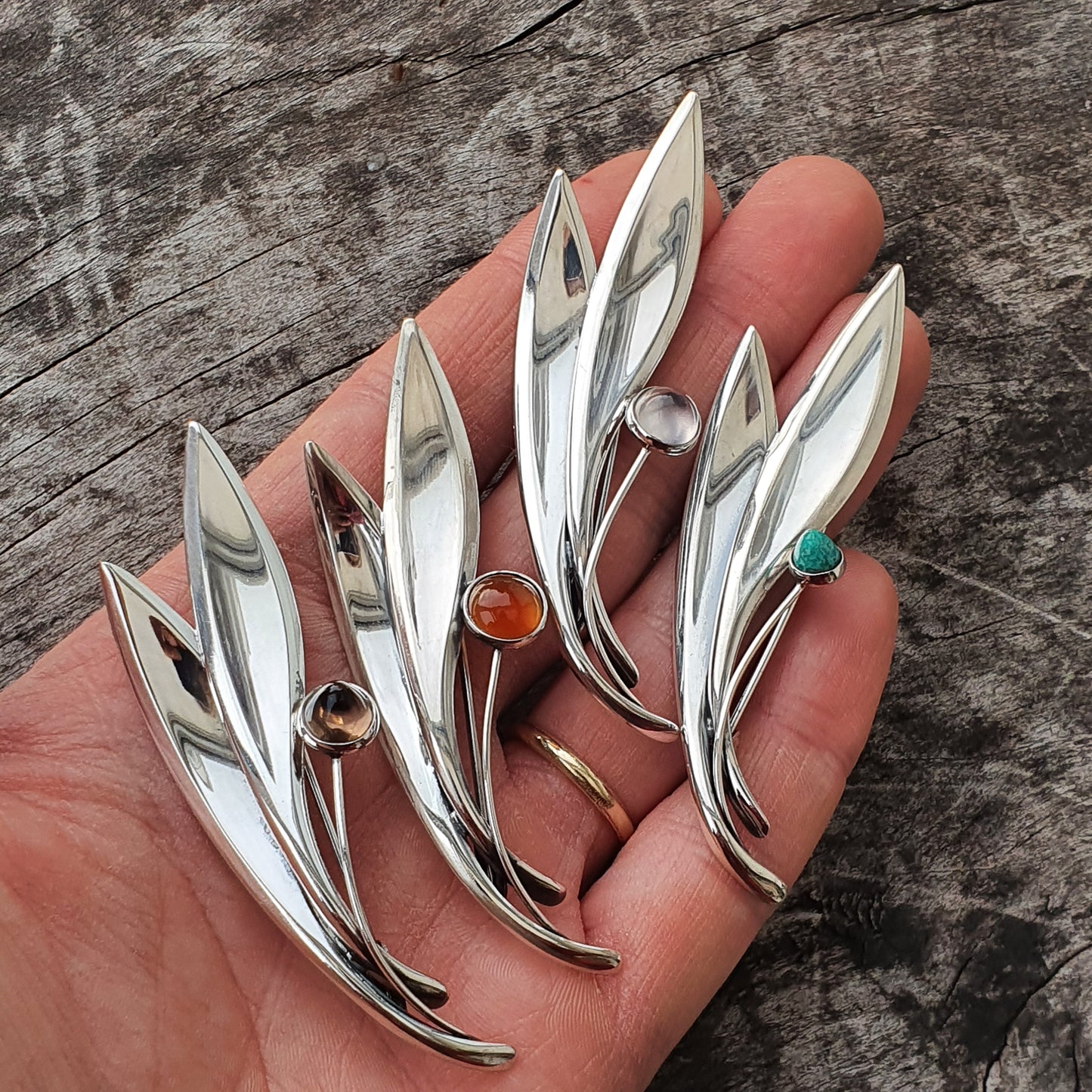 Silver leaf-shaped brooches or pins with gemstone accents.