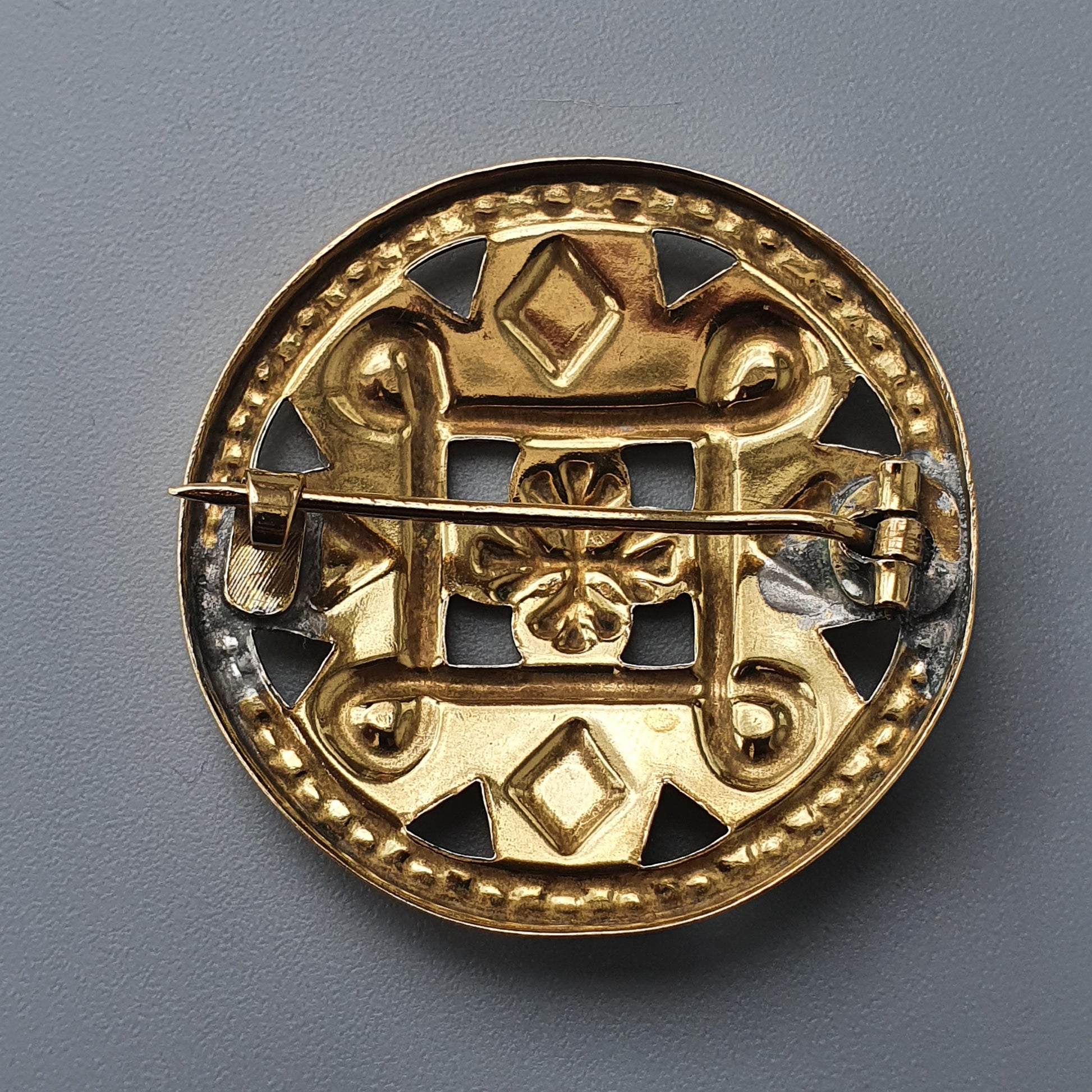 Ornate golden brooch or medallion with intricate geometric and floral designs.