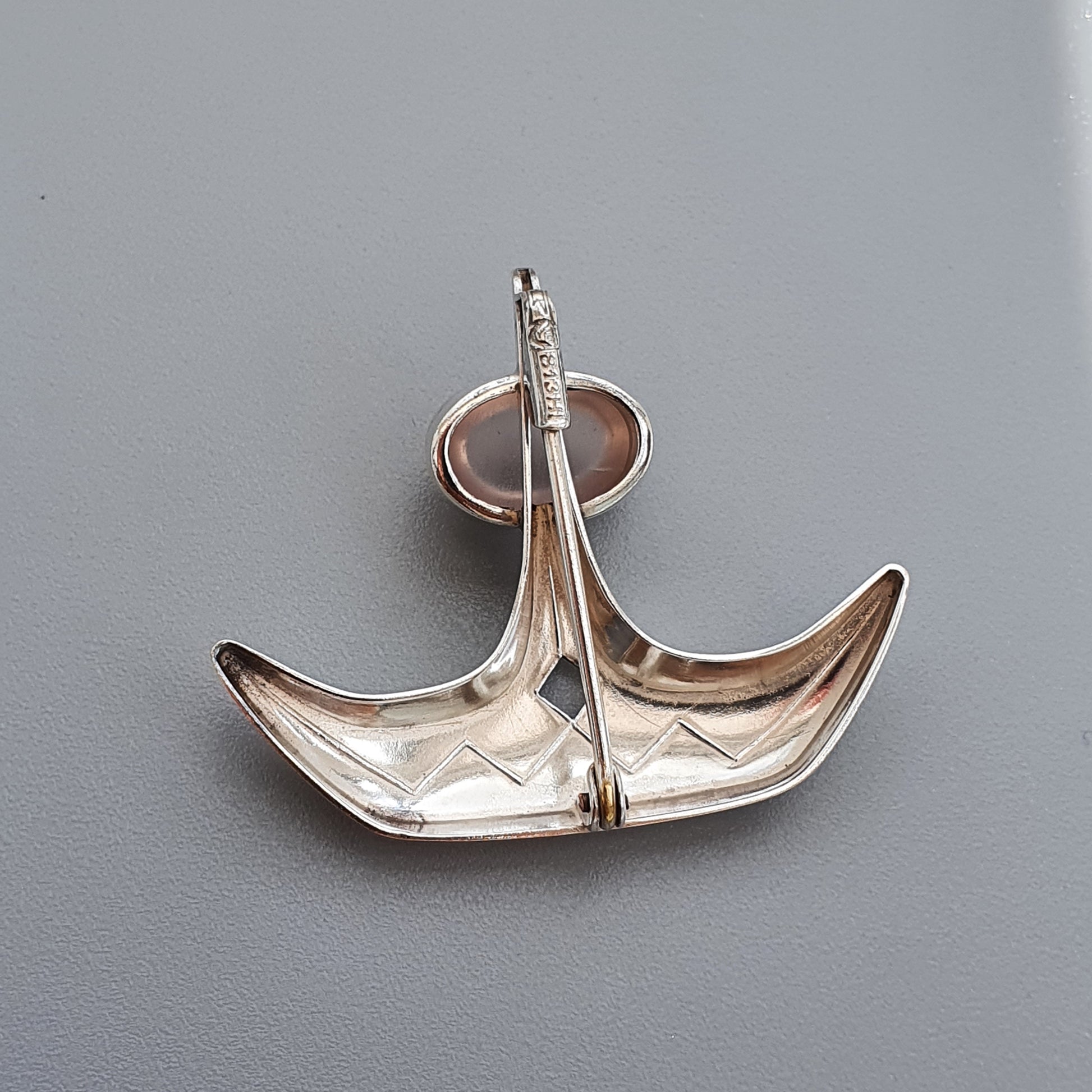 Silver anchor-shaped pendant or brooch with a sleek, modernist design.