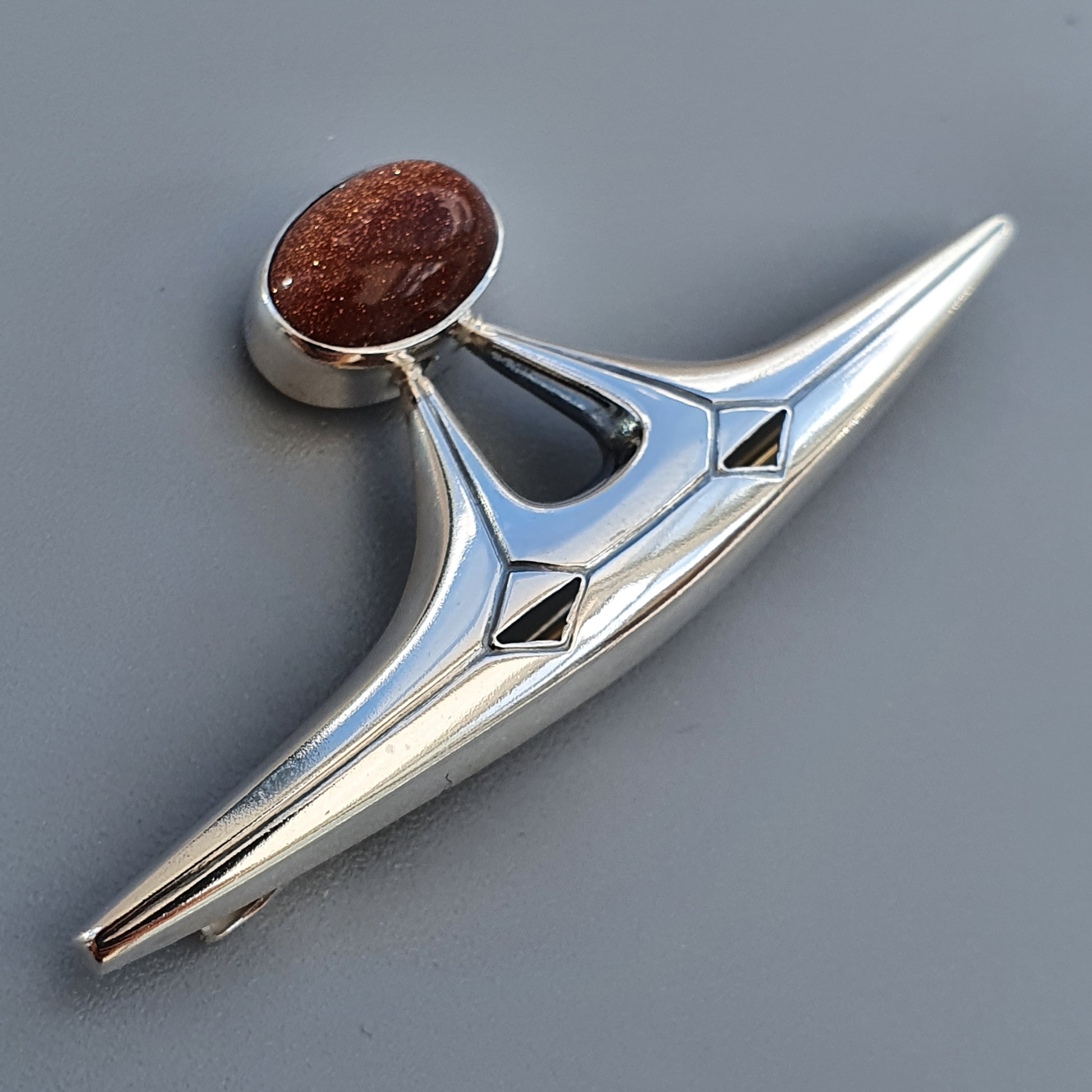 Sleek, retro-styled car hood ornament with a red circular accent.