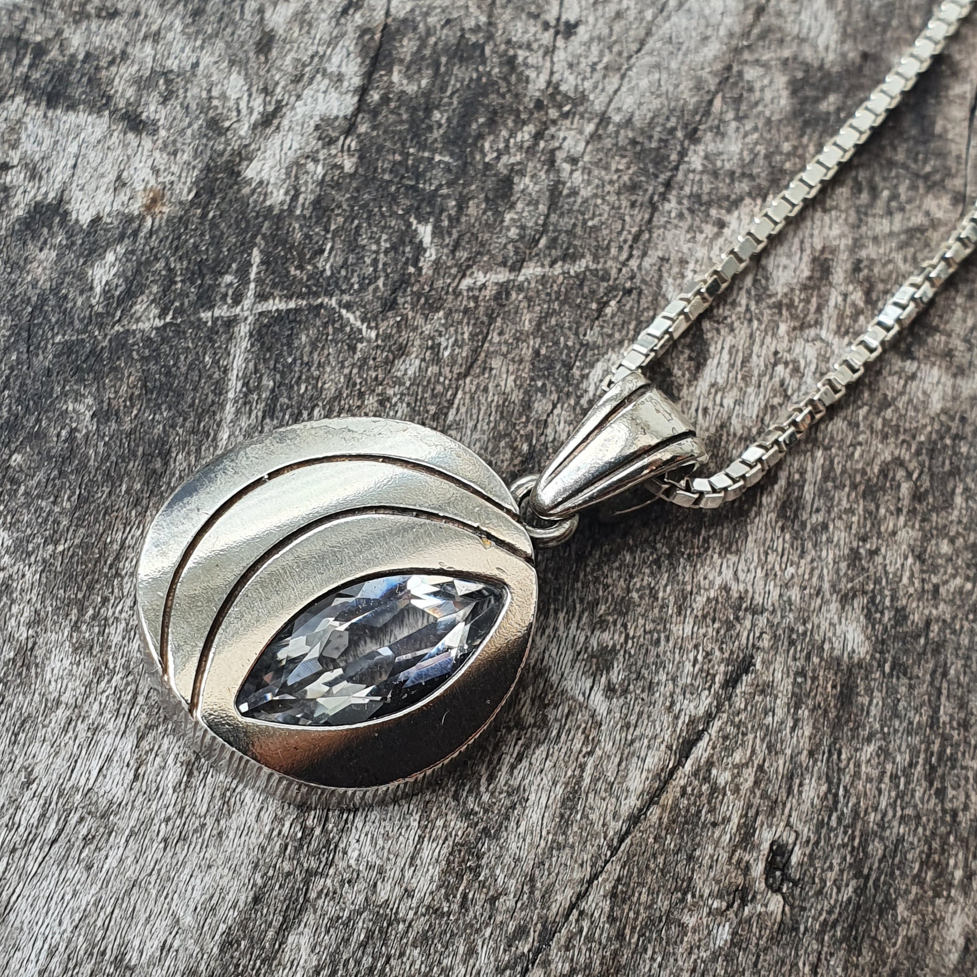 Silver pendant necklace featuring a marquise-cut gemstone in an abstract setting.