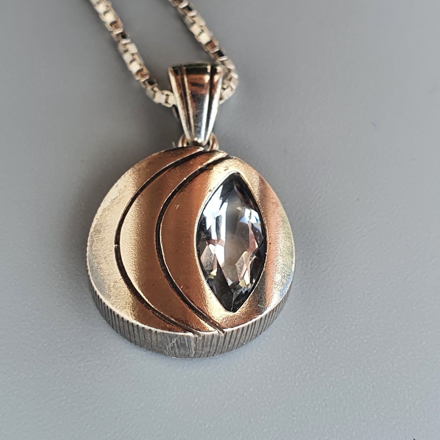 Pendant necklace featuring a mixed-metal design with a marquise-cut gemstone.