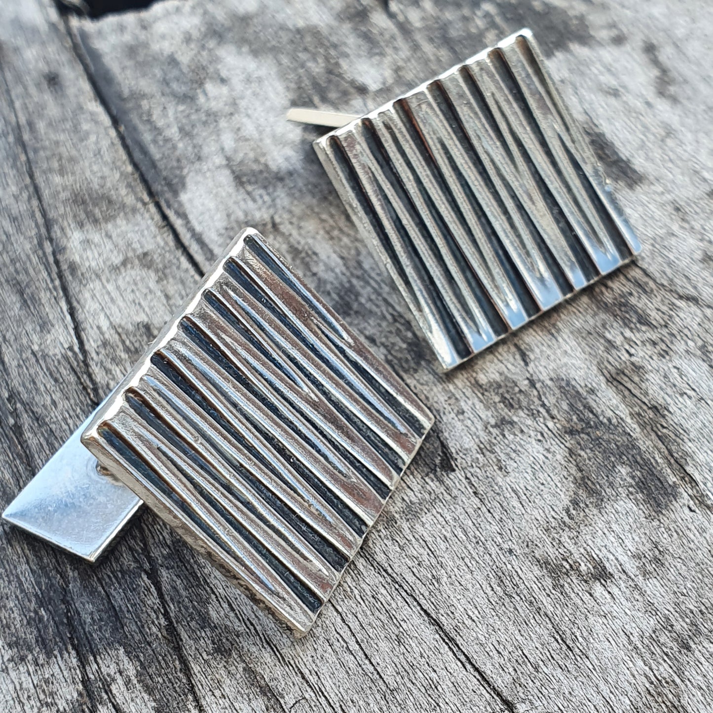 Pair of square silver earrings with parallel vertical lines.