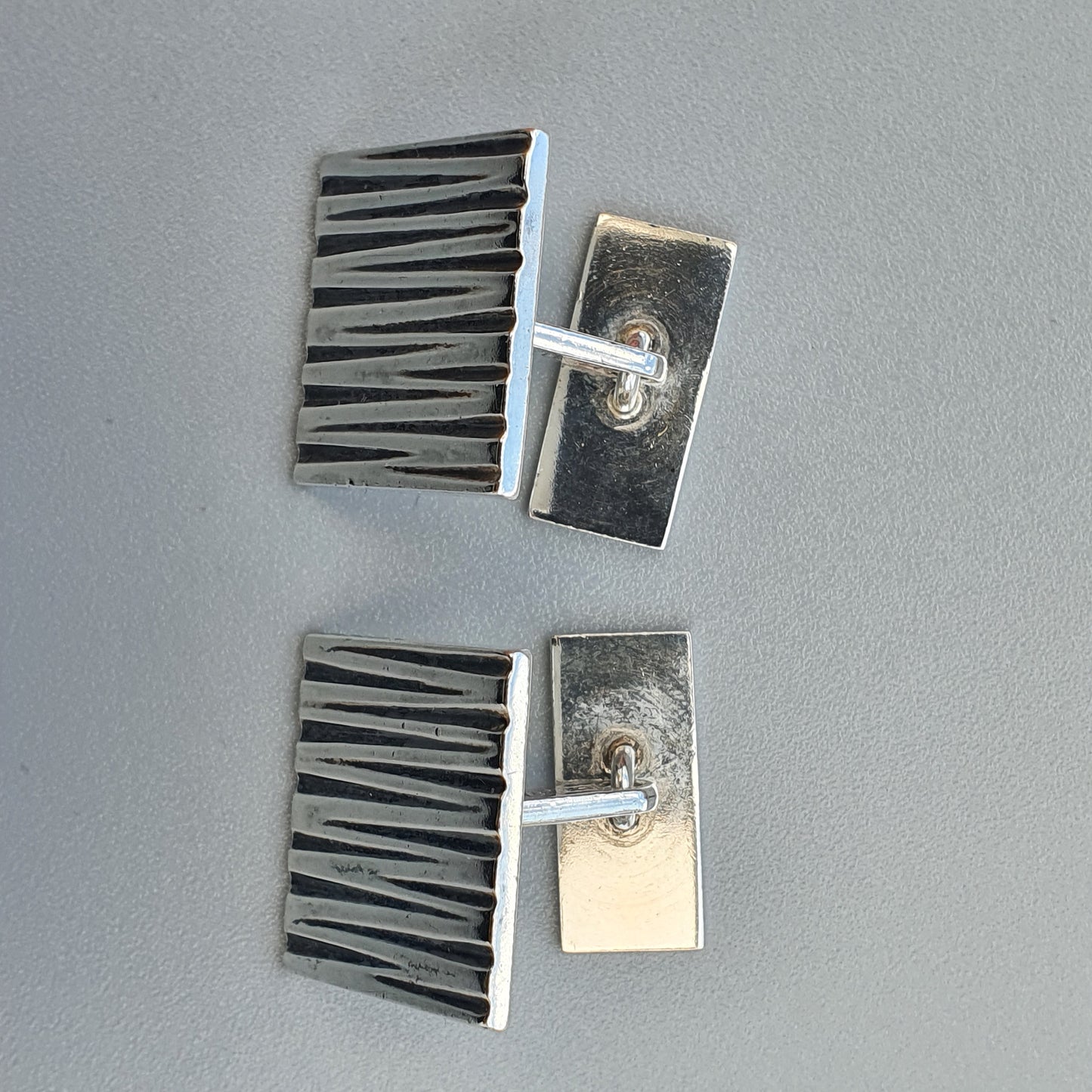 Pair of industrial-style metal cufflinks with ribbed designs.