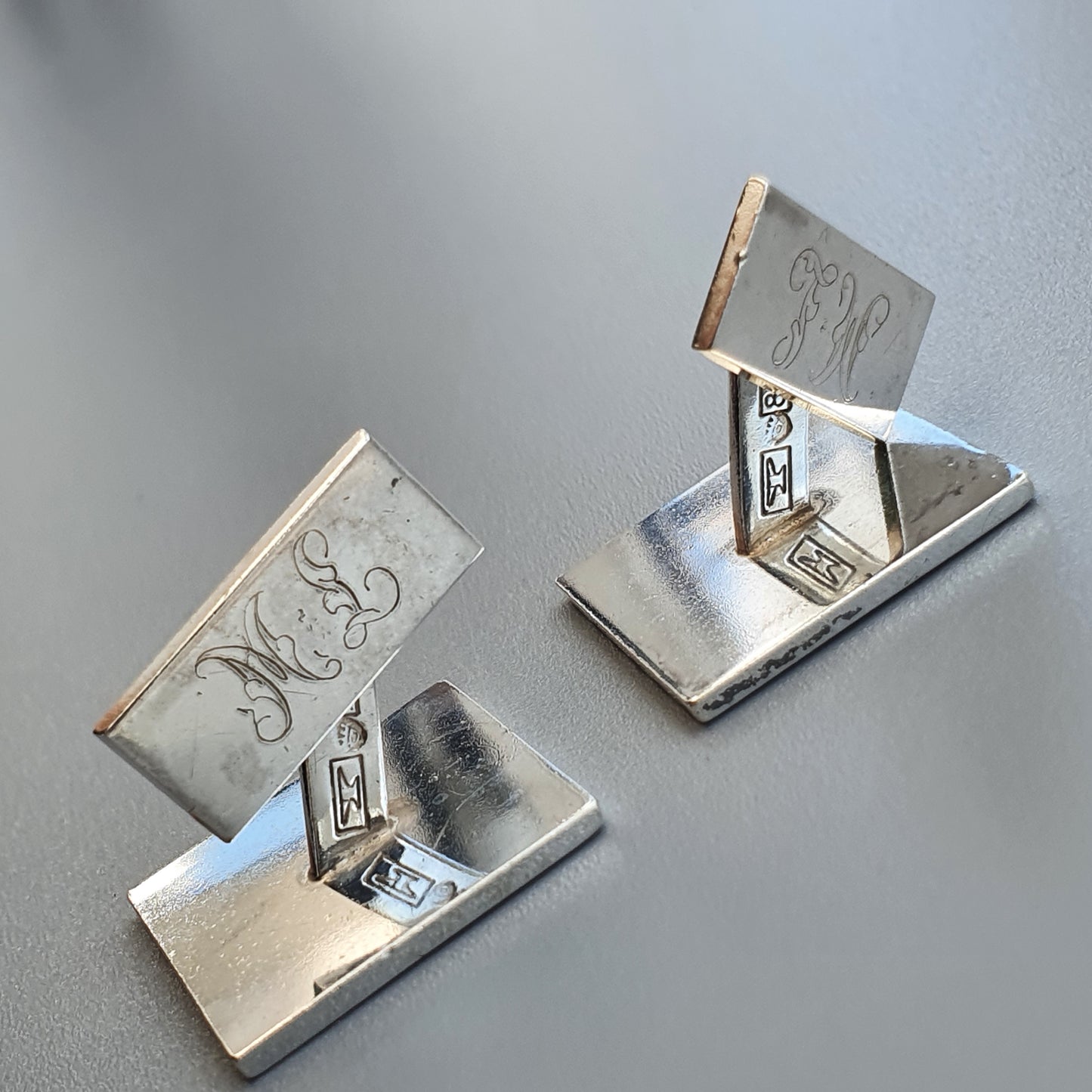 Silver-colored metal business card holders with engraved monograms.