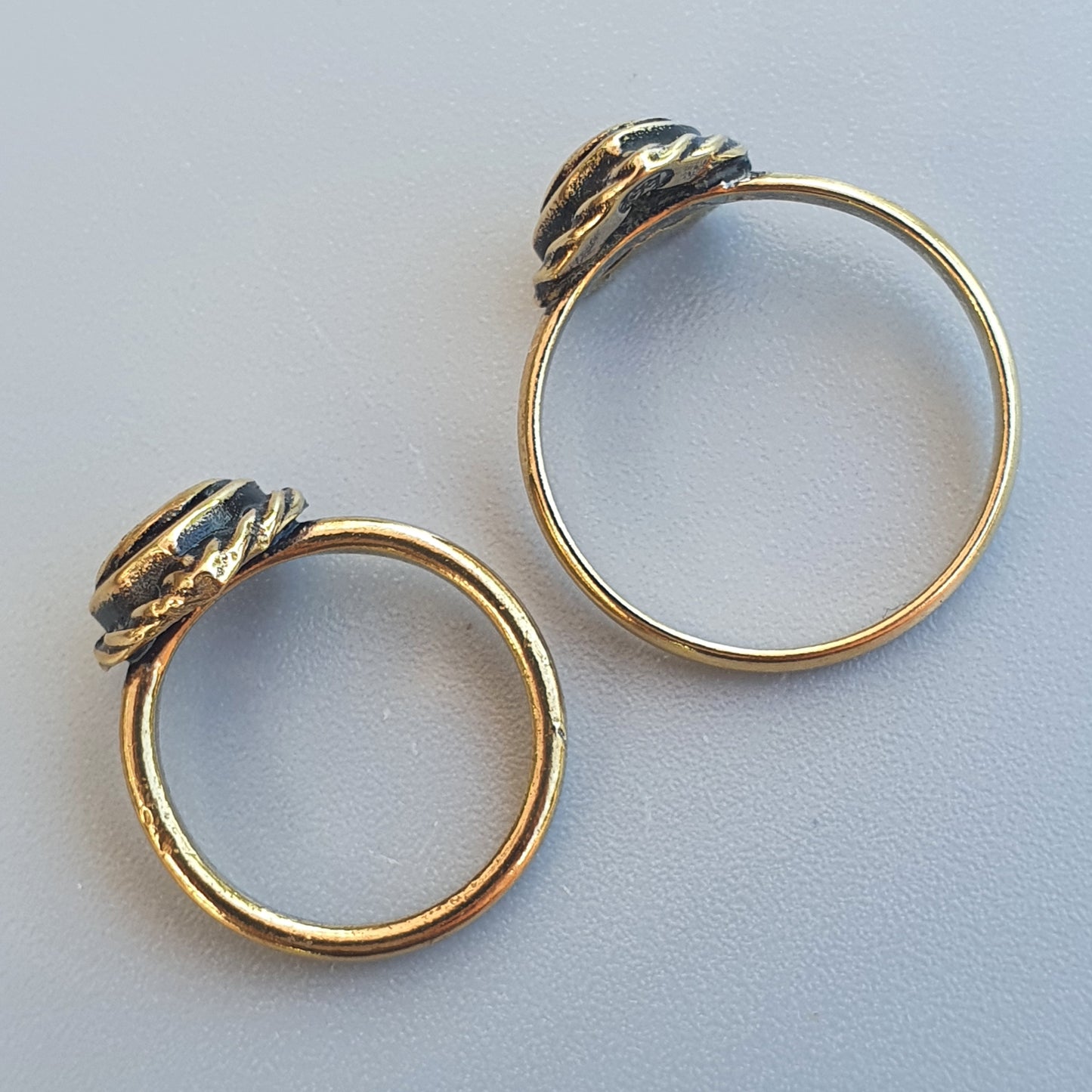 Pair of gold-toned rings with decorative elements on top.