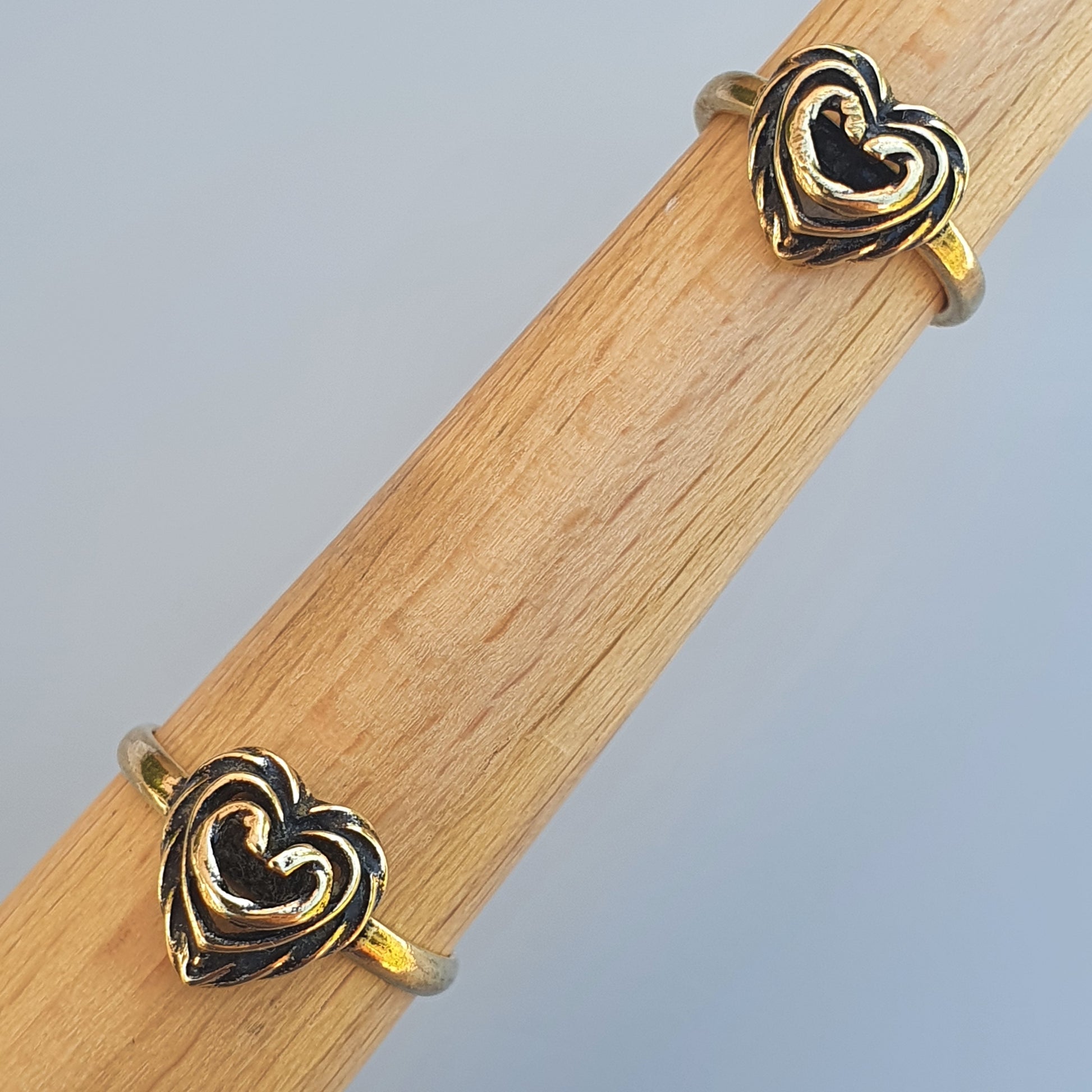 Heart-shaped gold rings displayed on a wooden surface.