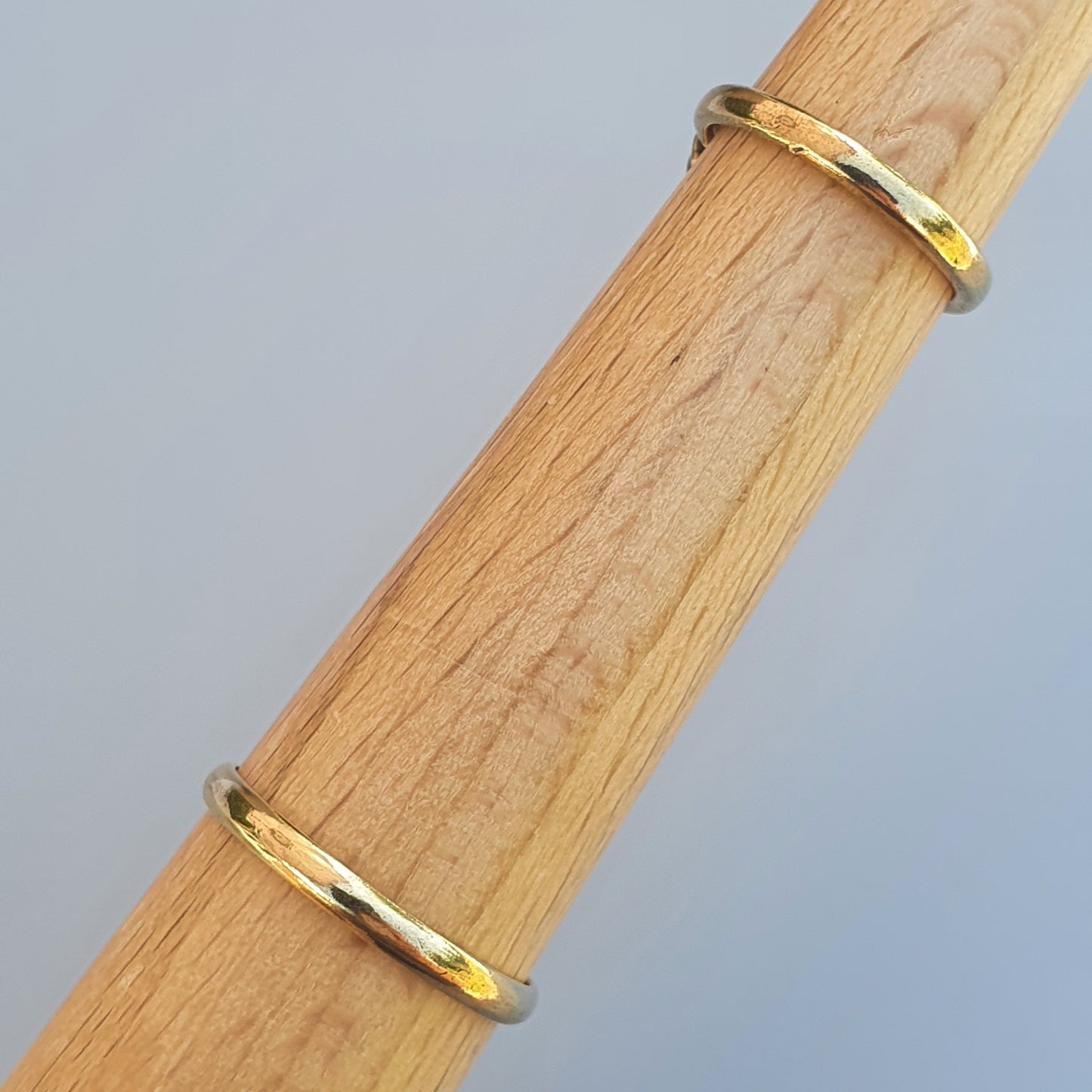 Thin gold-colored metal bands wrapped around a wooden dowel or rod.