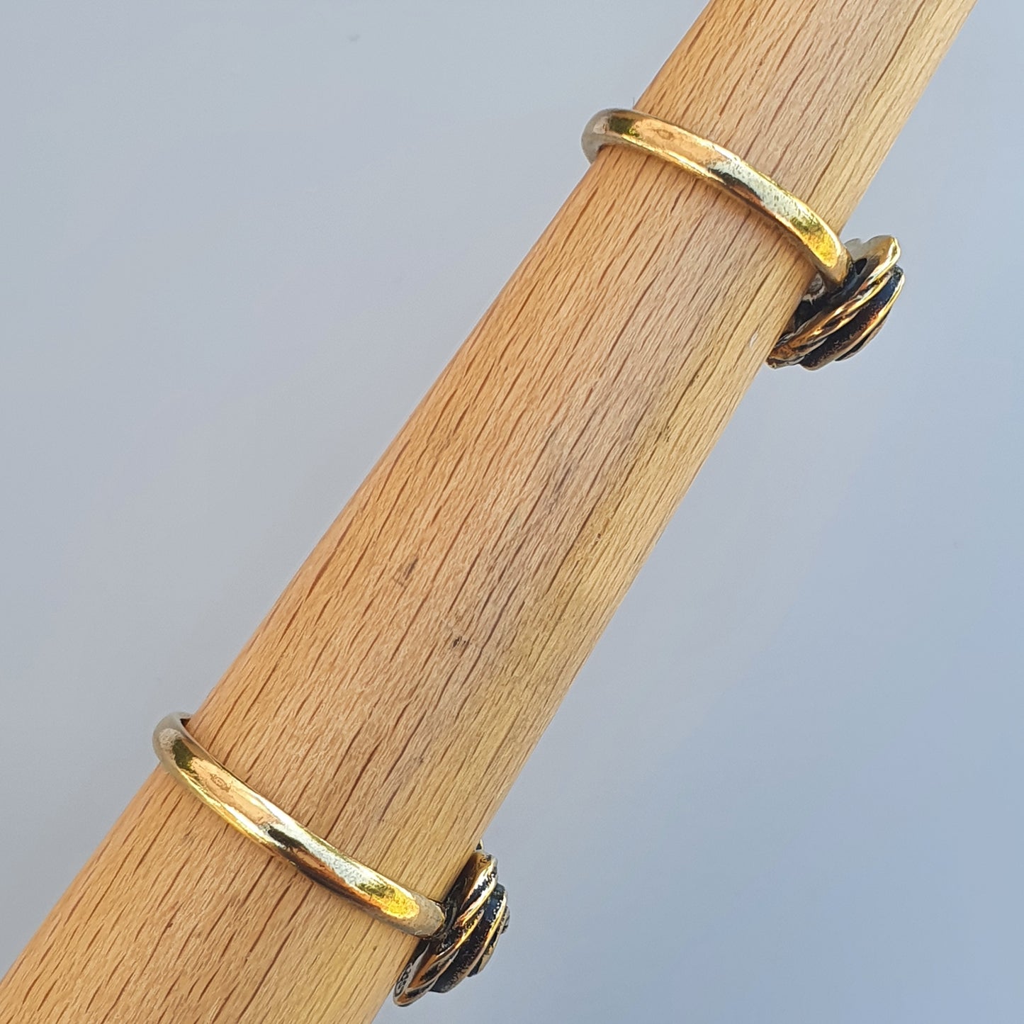 Gold hoop earrings with black accents displayed on a wooden surface.