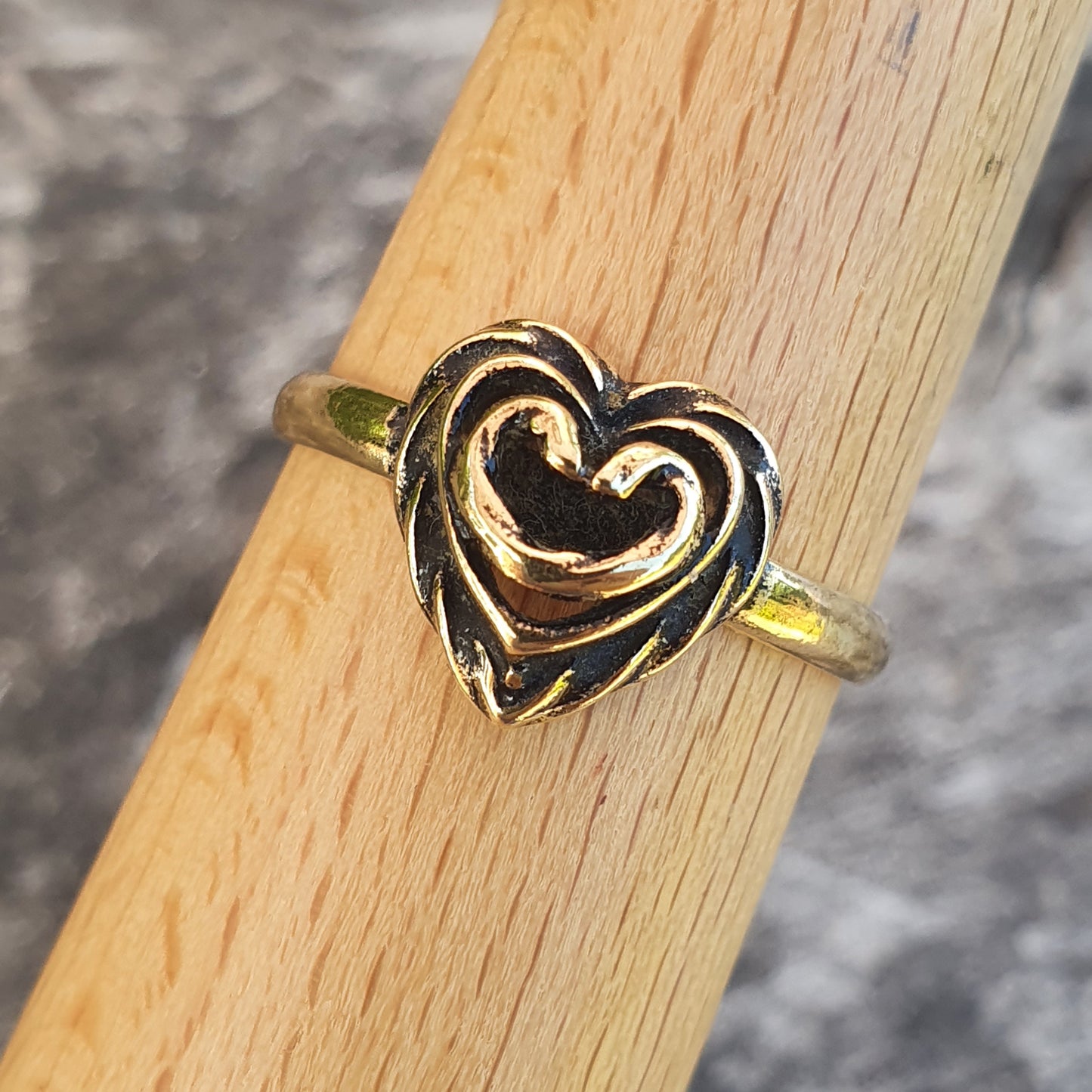 Heart-shaped gold and silver ring on a wooden surface.