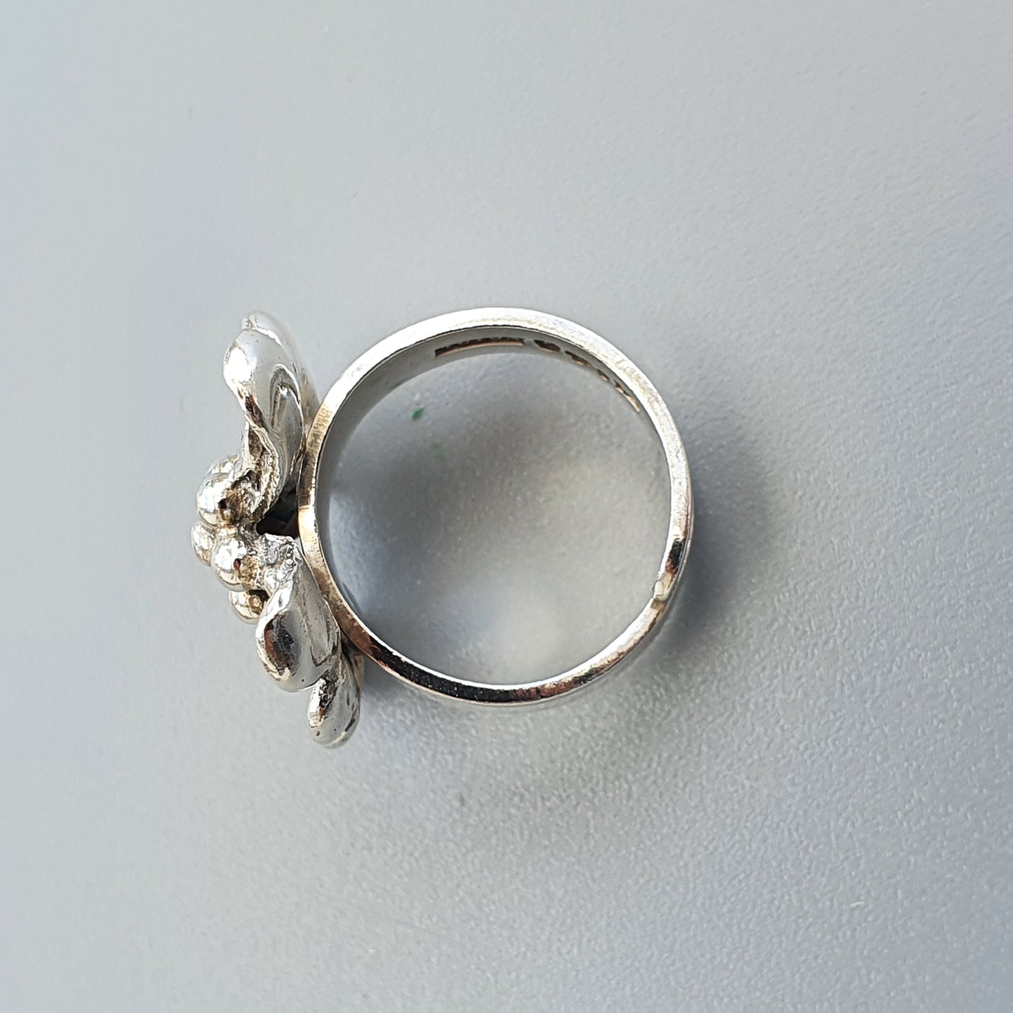 Silver ring with a floral or butterfly-shaped design on top.