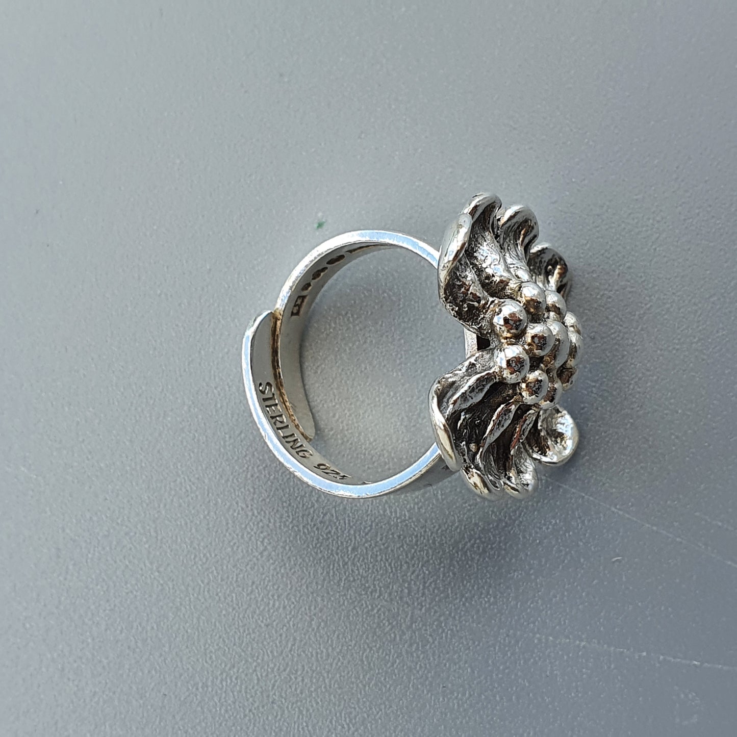 Silver ring with an intricate floral or coral-like design on top.