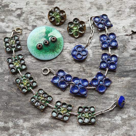 Handmade jewelry pieces featuring blue and green glass or enamel flower designs.