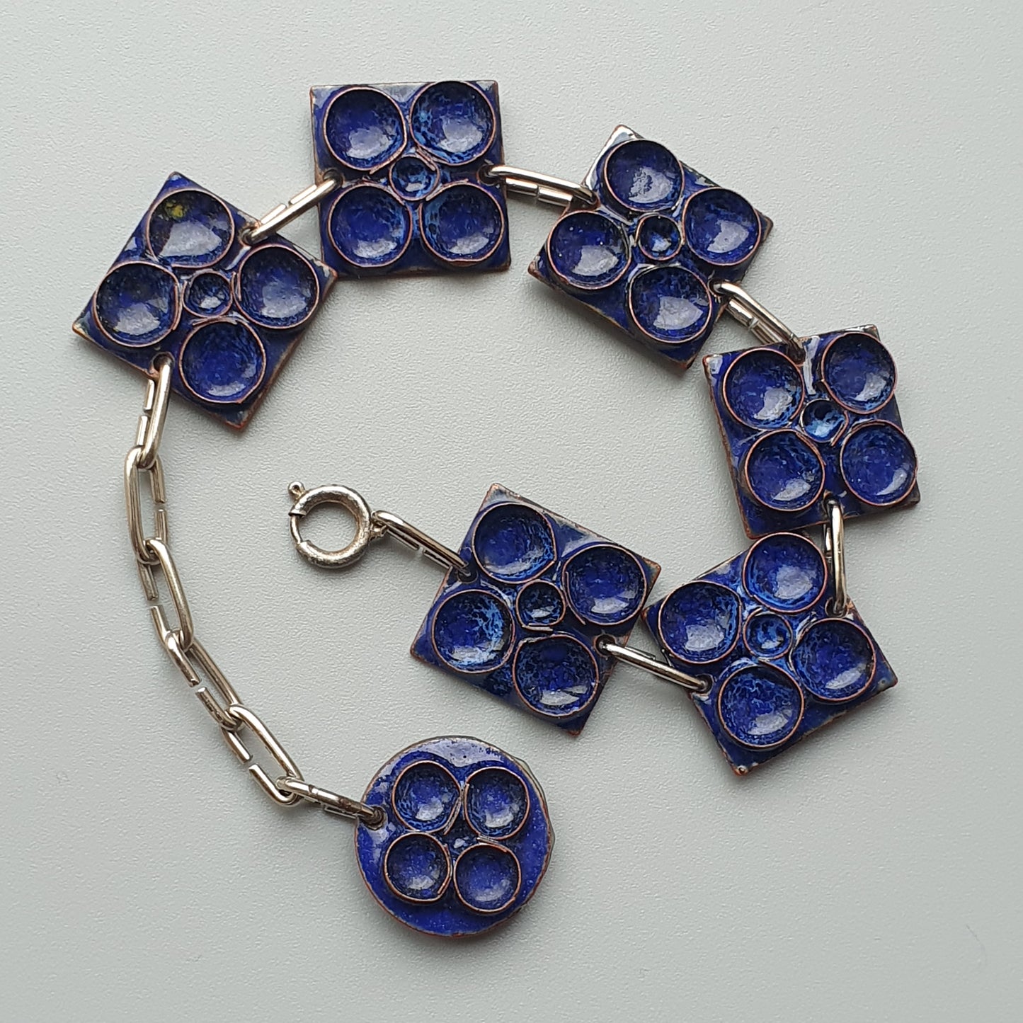 Bracelet composed of linked blue enamel geometric shapes.