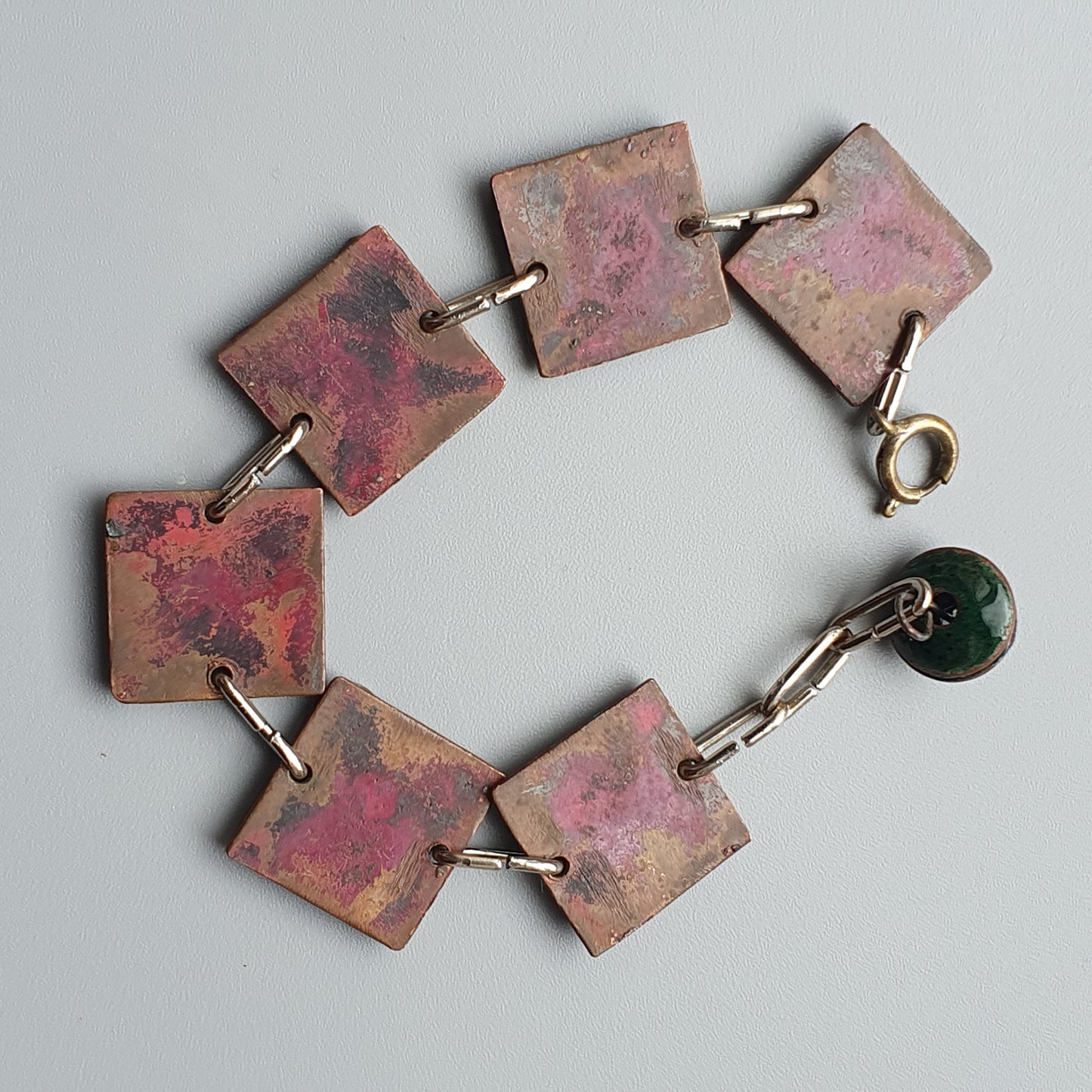 Handcrafted bracelet with square copper-colored links and a green bead charm.