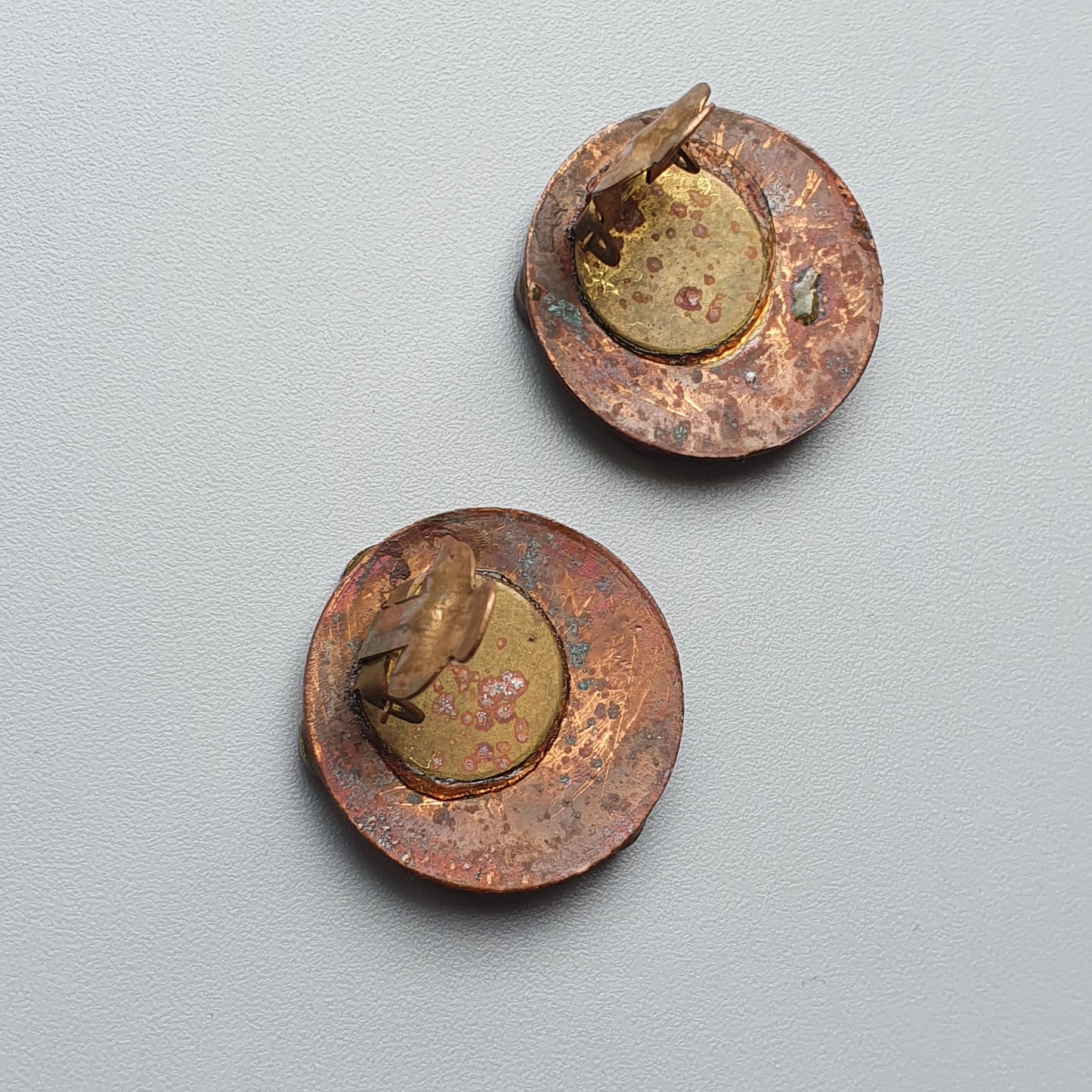 Two ancient-looking copper or bronze coins with gold-colored centers.