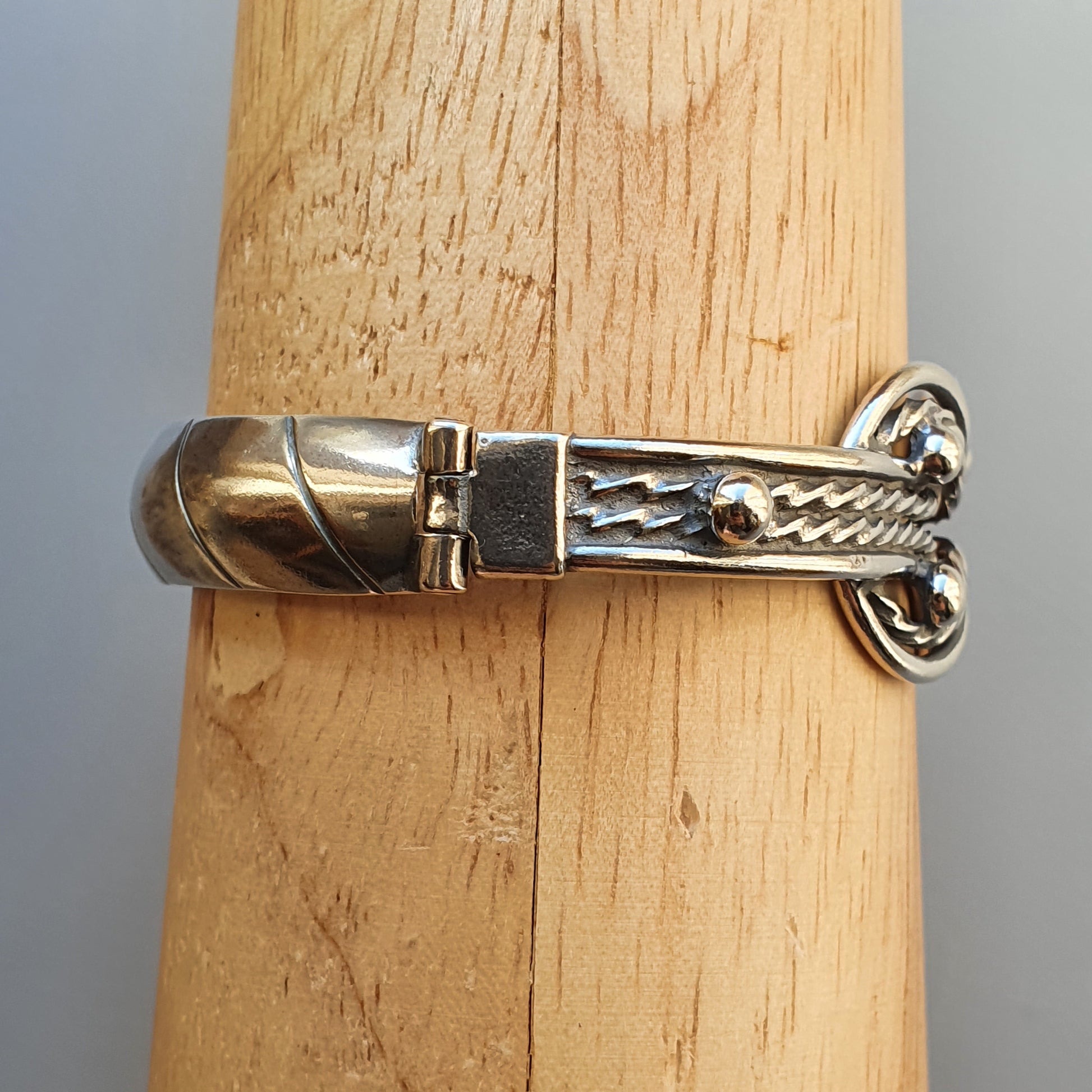 Silver bracelet with a decorative clasp featuring a twisted rope design.