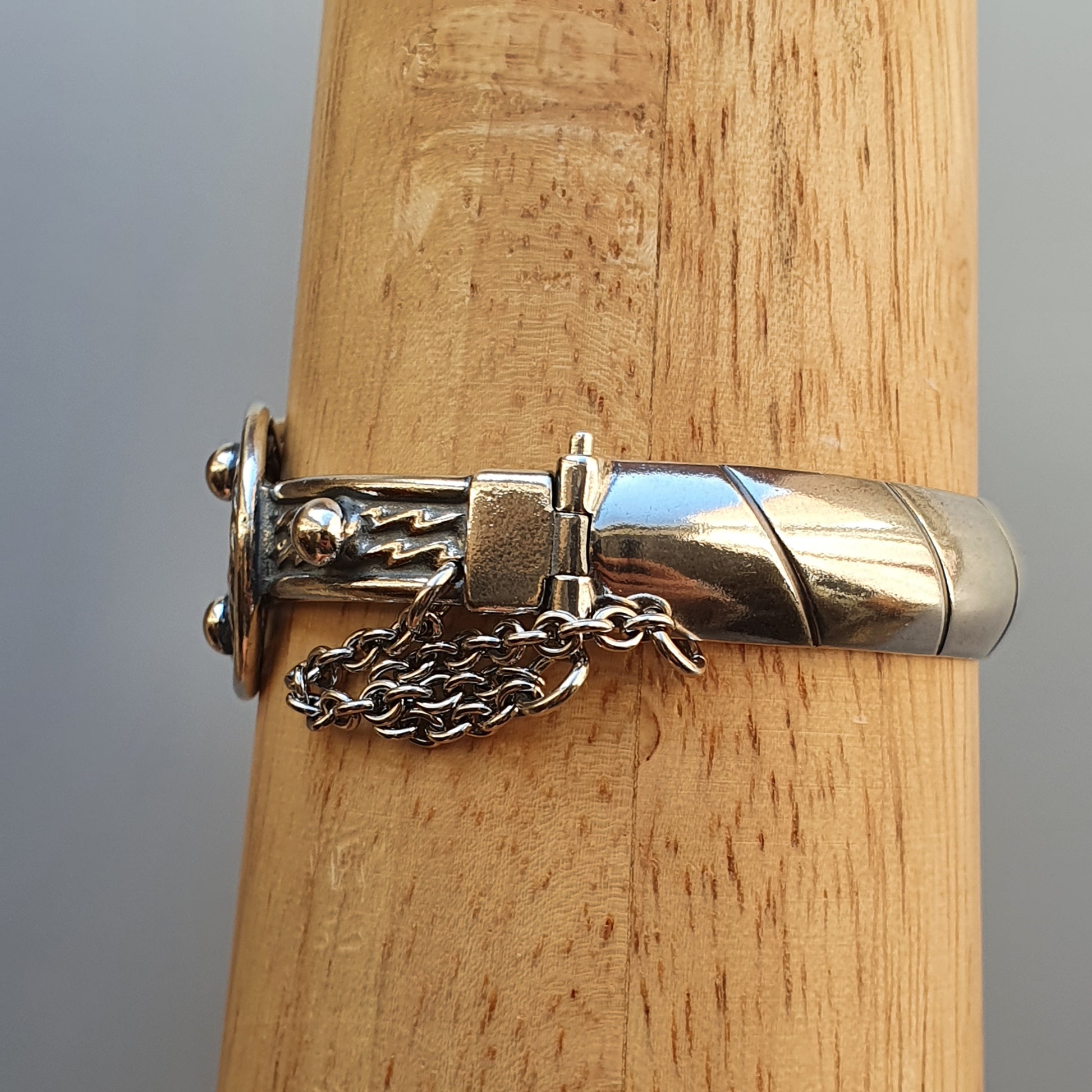 Silver whistle with an attached chain, featuring an ornate design.