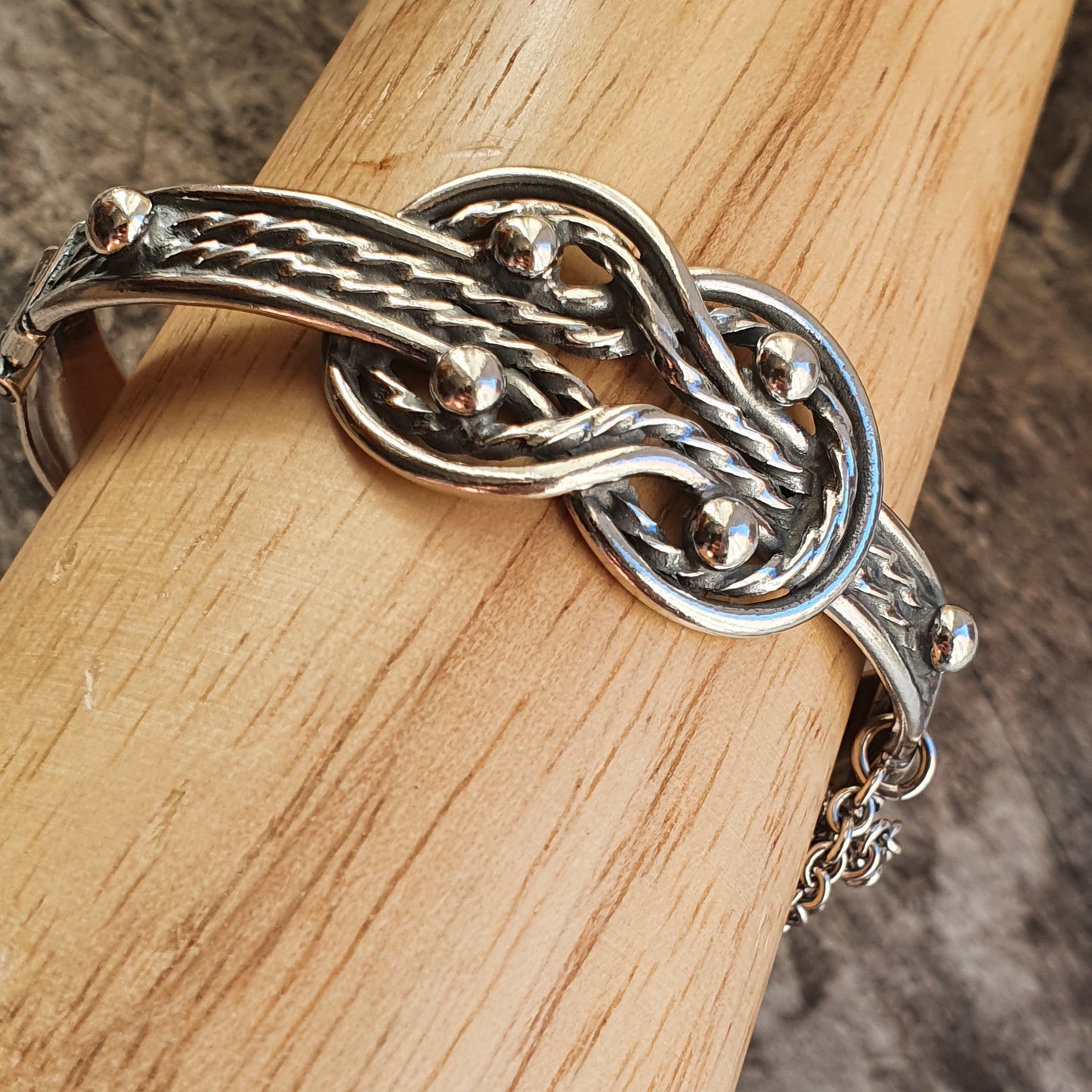 Intricately designed silver bracelet with a twisted knot pattern.