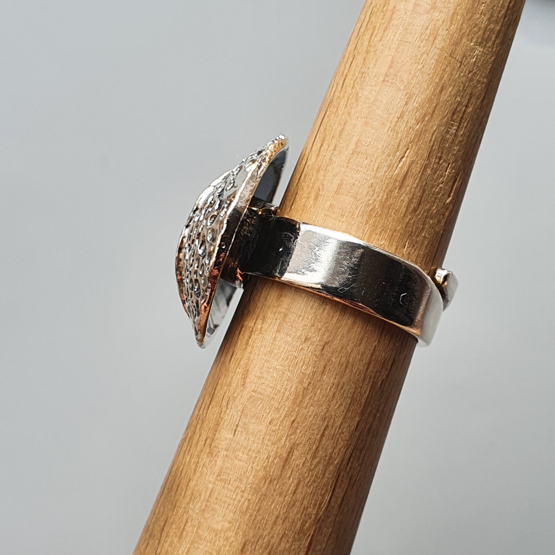 Silver ring with a decorative half-circle shaped top featuring a textured or patterned surface.