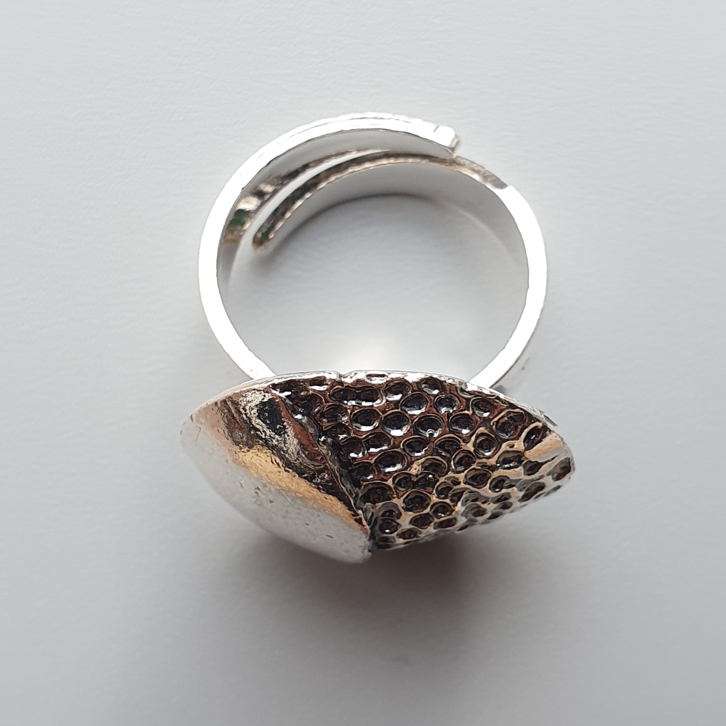 Silver ring with a textured, fan-shaped ornament on top.