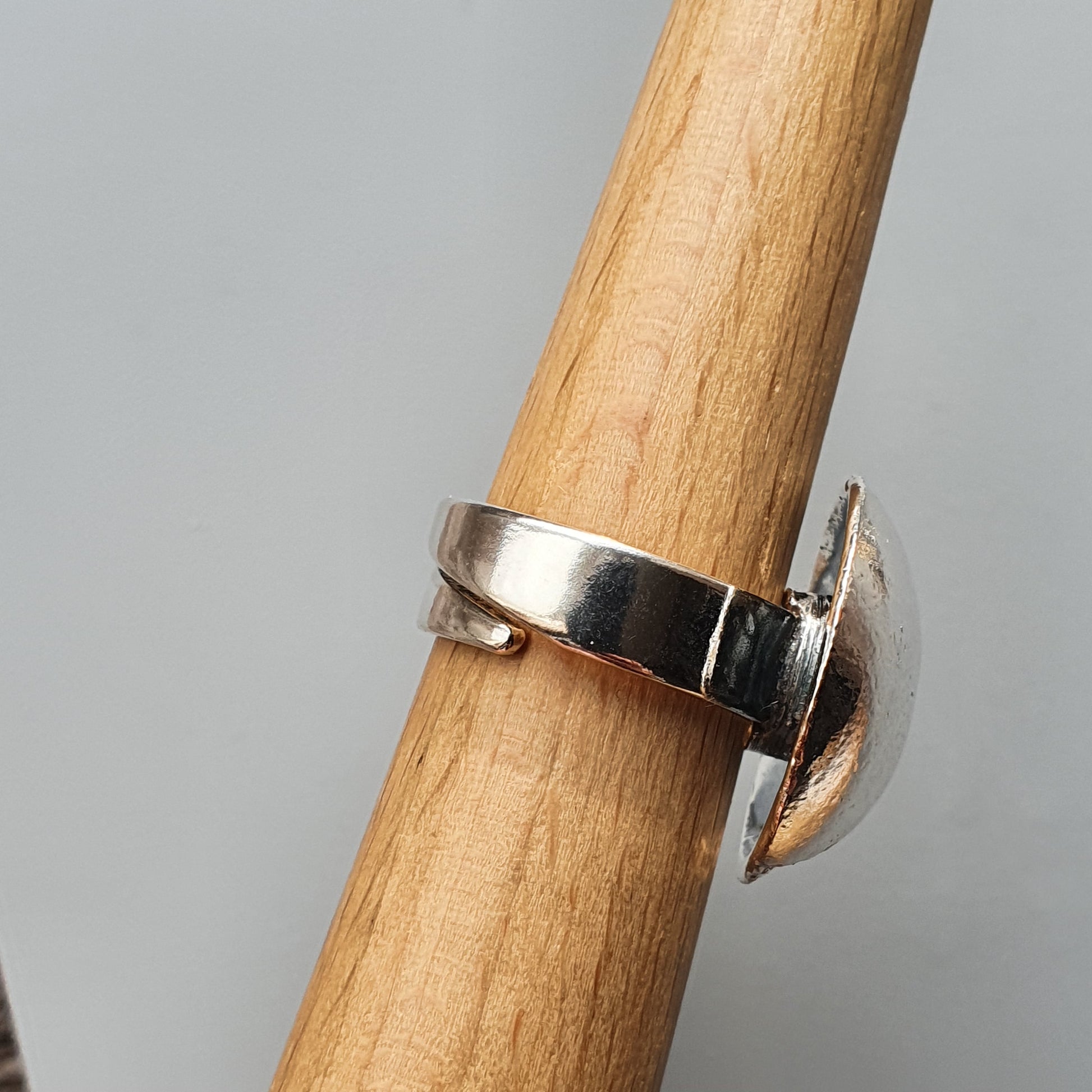 Silver ring with a crescent moon-shaped design on a wooden surface.