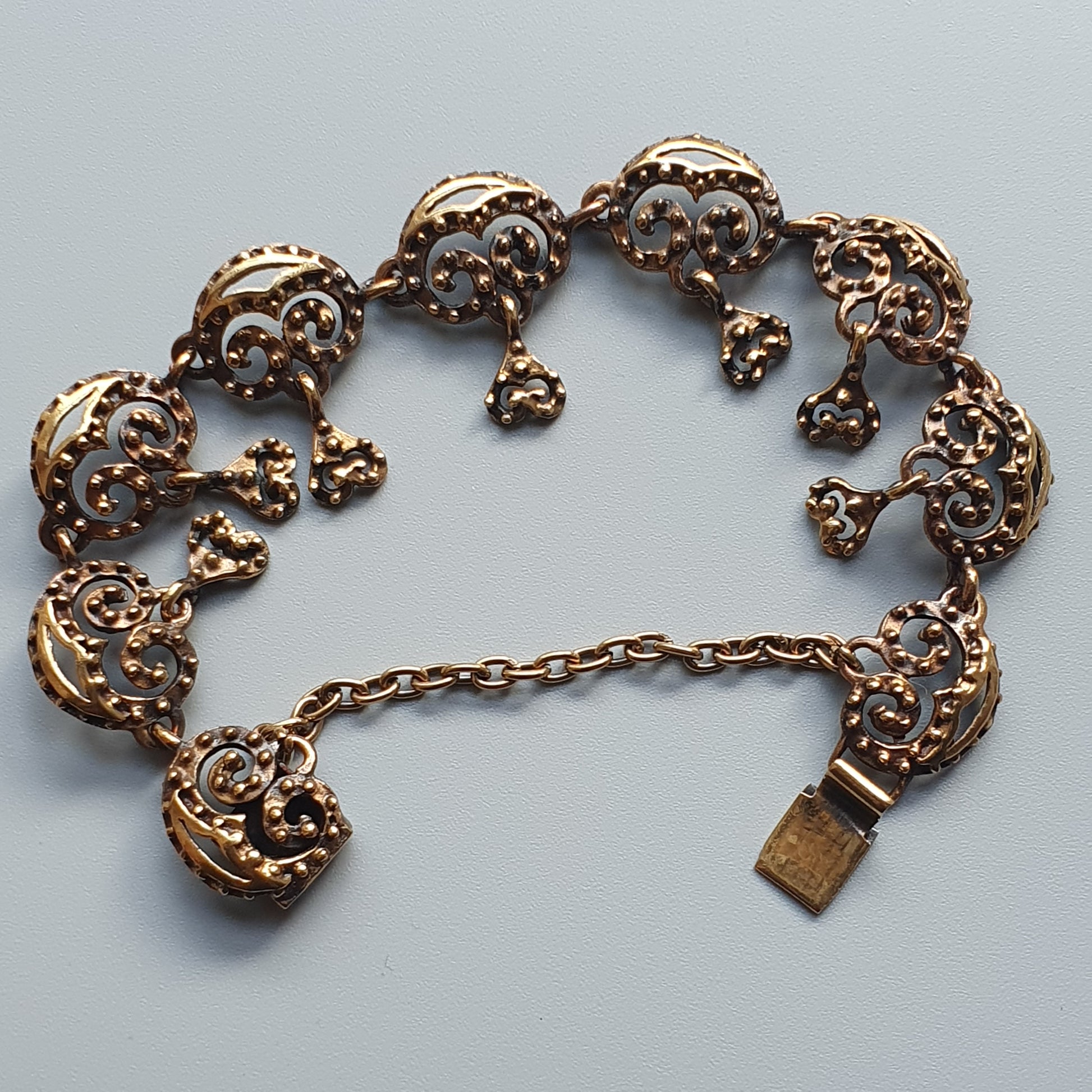 Ornate gold-toned bracelet with crescent moon-shaped links and dangling elements.