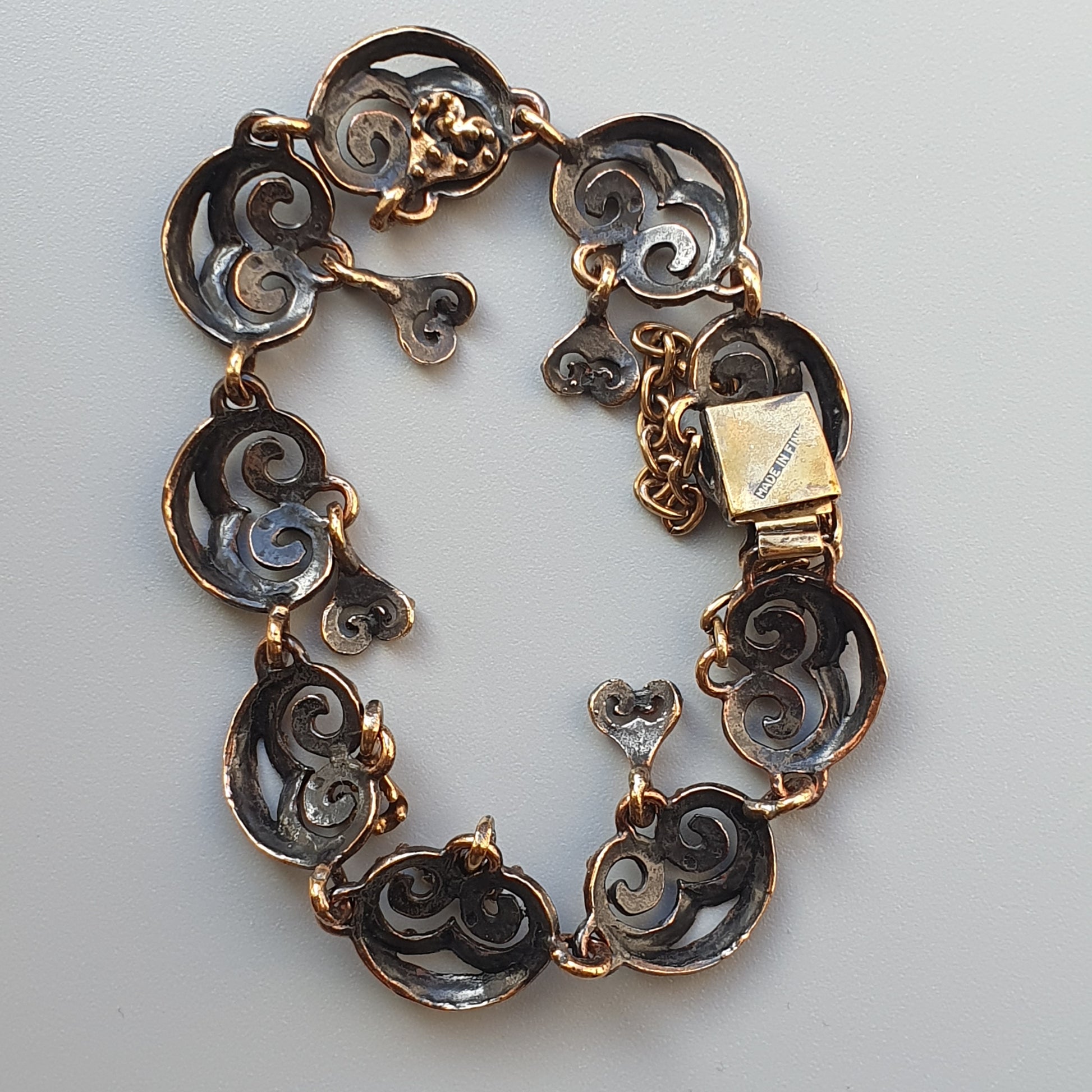 Ornate gold and silver bracelet with swirling filigree designs in each linked segment.