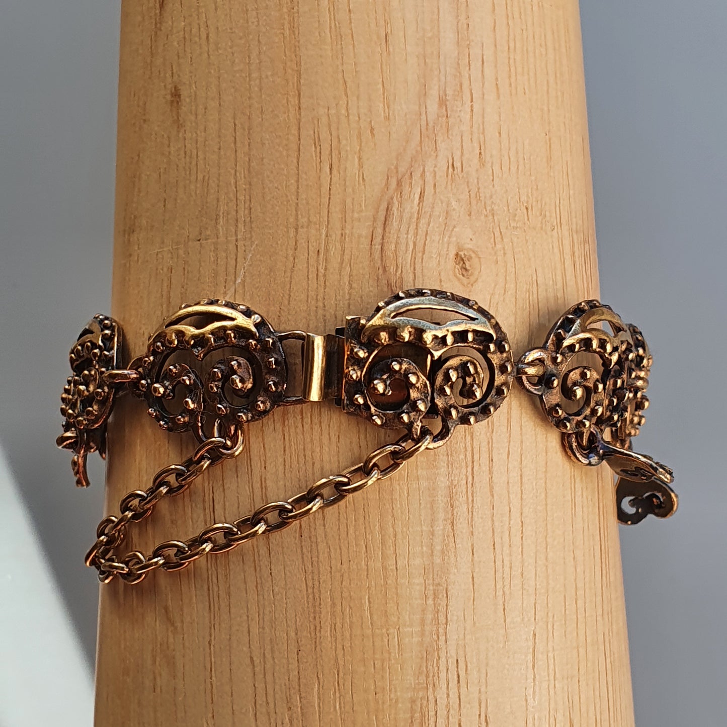 Ornate gold-toned bracelet with decorative circular links and a safety chain.