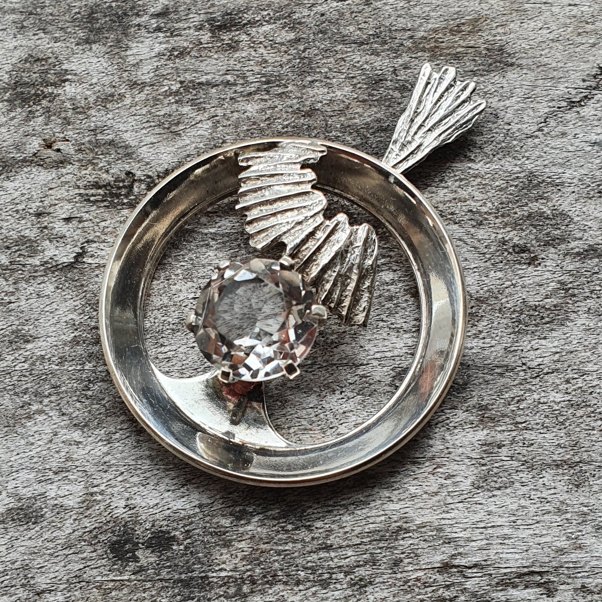 Silver pendant featuring a stylized bird design with a gemstone as the body.