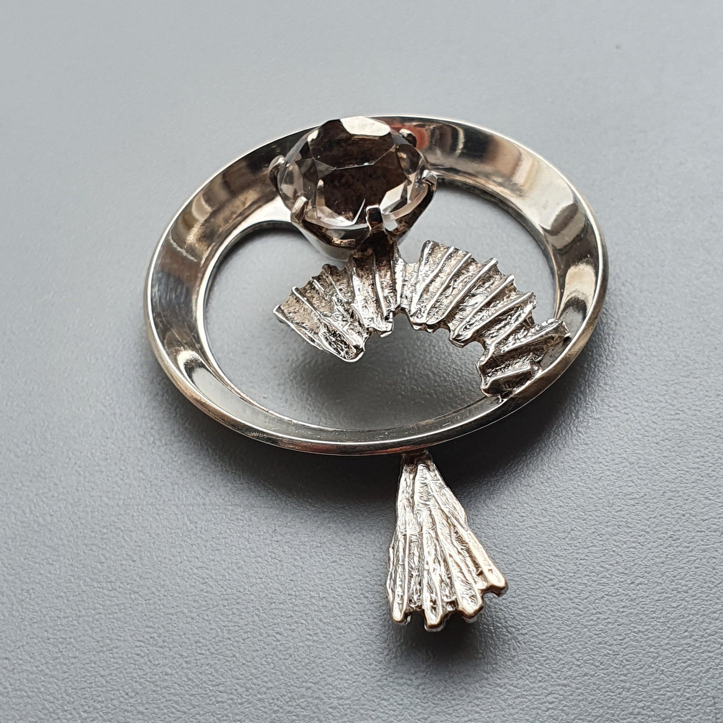 Silver brooch or pin shaped like a stylized bird with a gemstone for its eye.