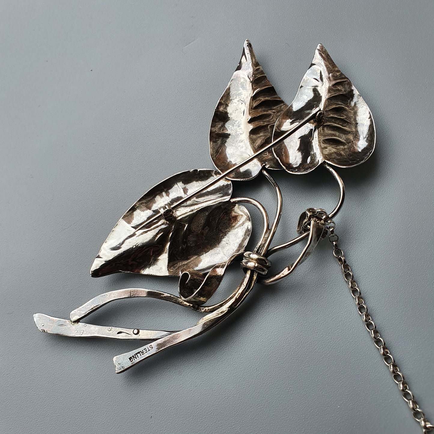 Silver brooch or pin shaped like stylized leaves or foliage.