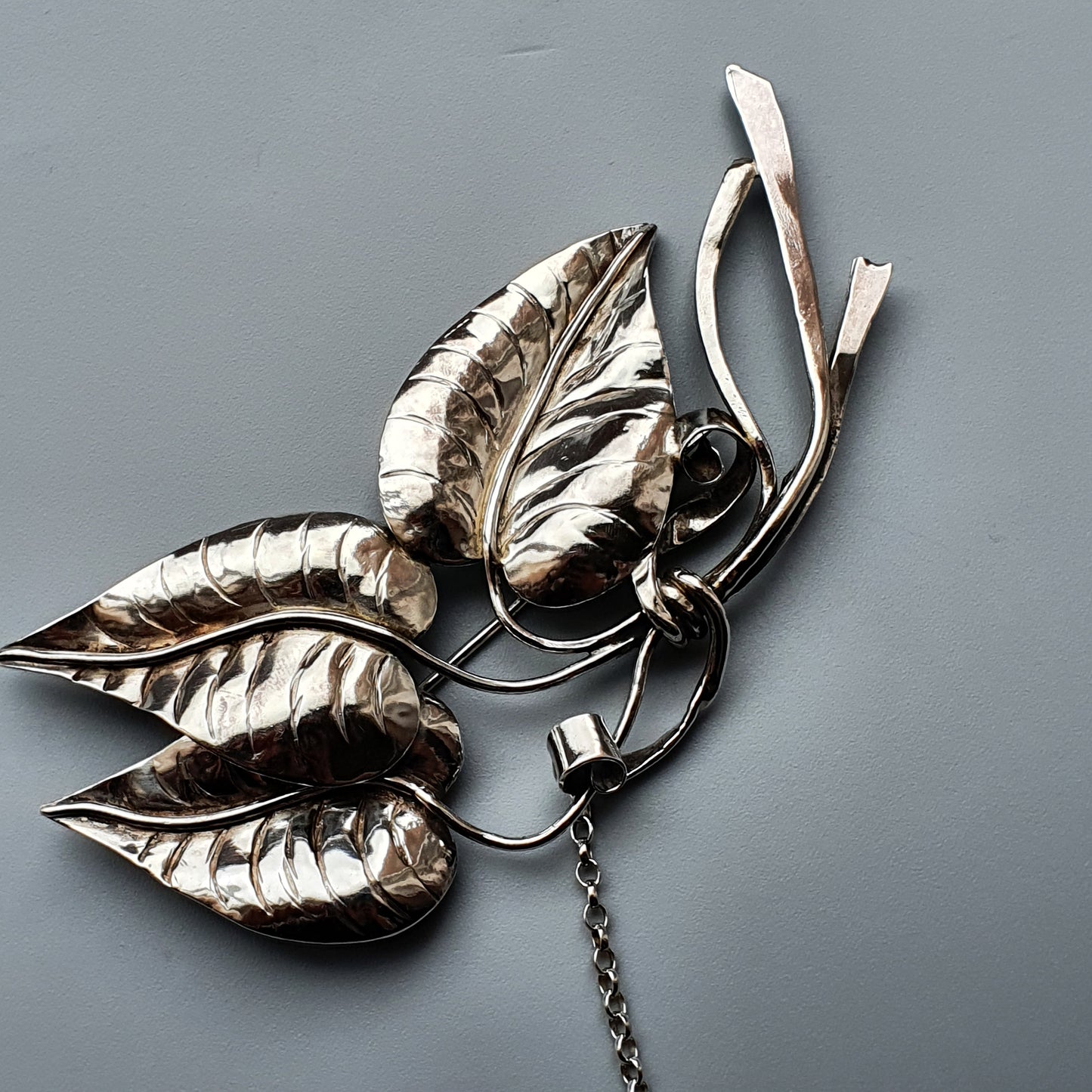 Silver leaf-shaped brooch or pendant with intricate metalwork details.