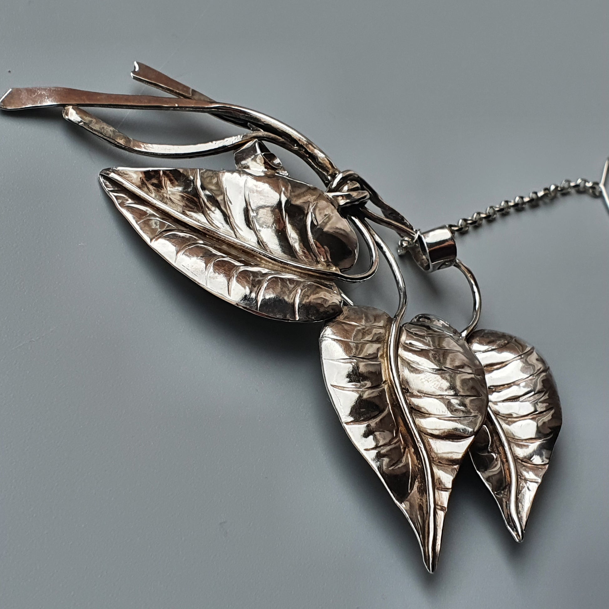 Silver pendant necklace featuring intricately detailed leaf-shaped charms.